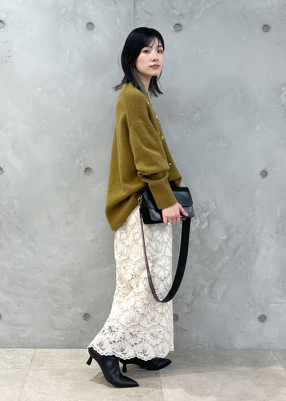 ブラック系のショルダーバッグ、ベージュ系のスカート、イエロー系のニット/セーターを着用したレディースの秋コーディネートの4枚目の写真