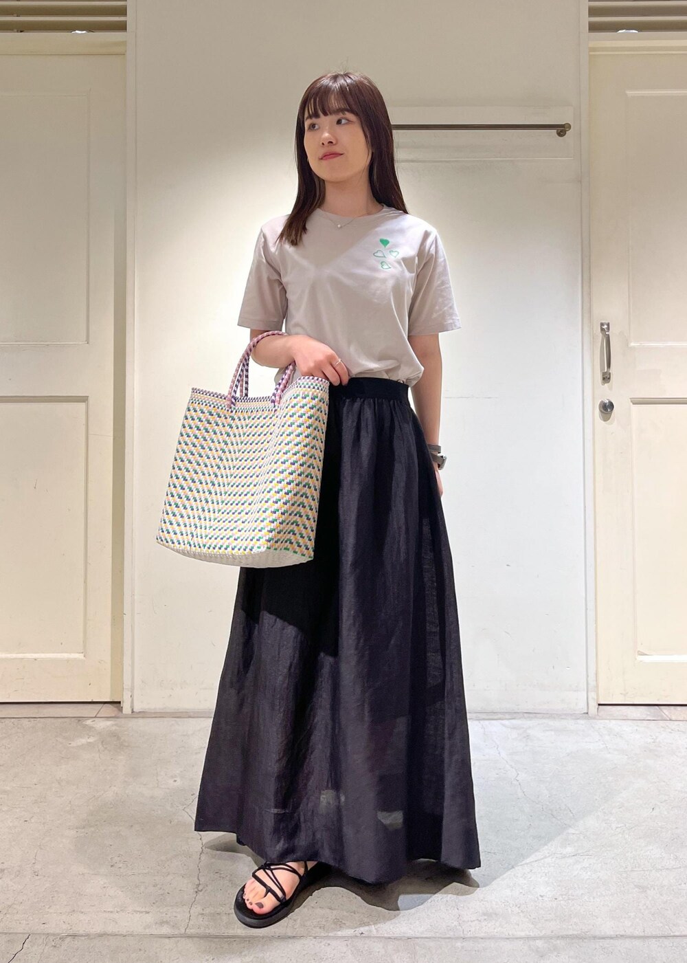 ブラック系のスカート、ベージュ系のTシャツ/カットソーを着用したレディースの夏コーディネートの2枚目の写真