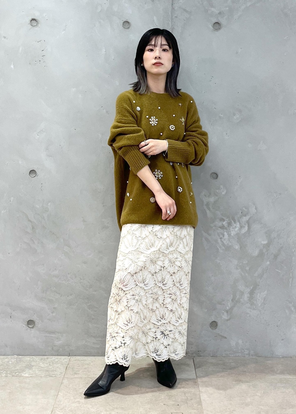 ブラック系のショルダーバッグ、ベージュ系のスカート、イエロー系のニット/セーターを着用したレディースの秋コーディネートの6枚目の写真