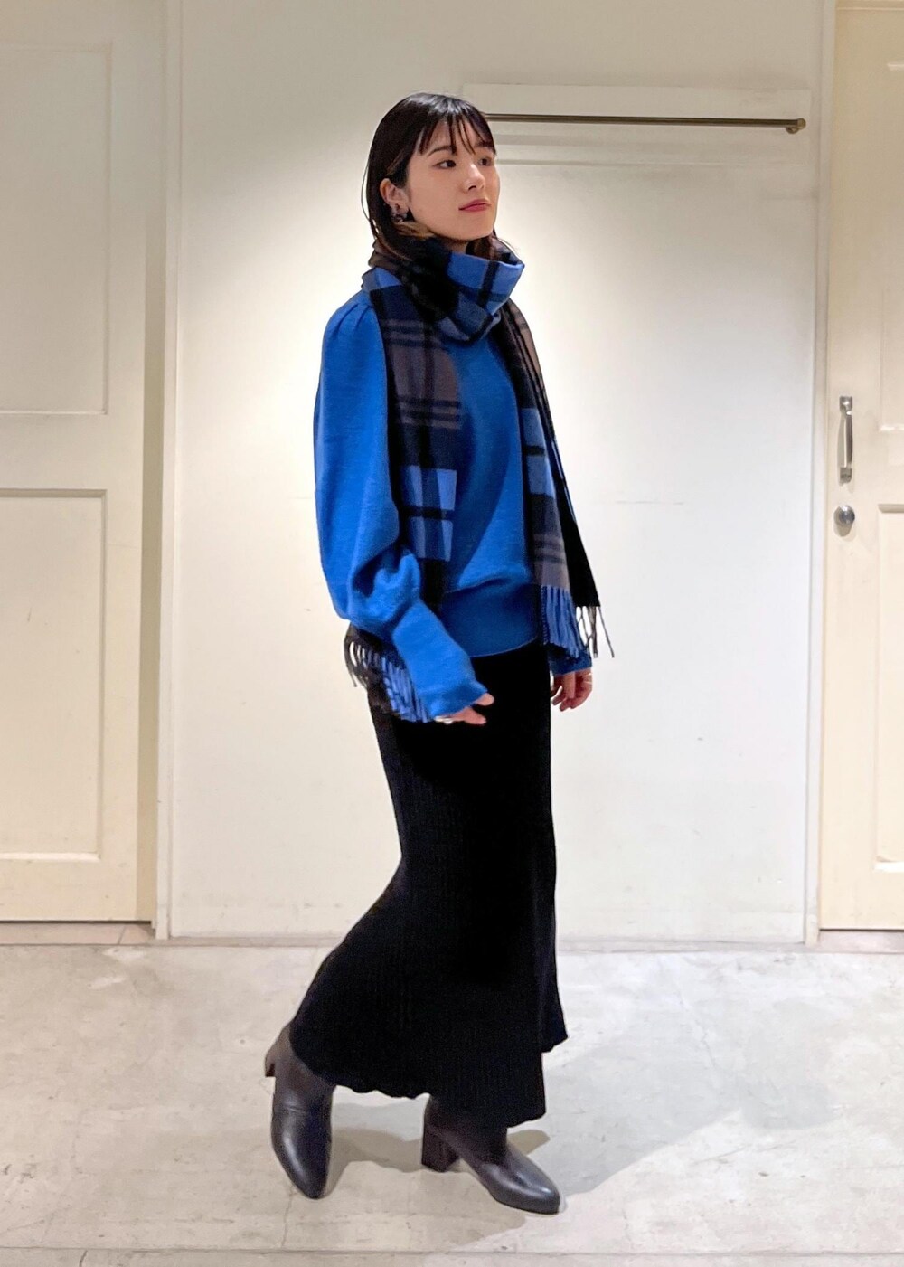 ブラック系のブーツ、ブラック系のスカート、ブルー系のニット/セーターを着用したレディースの秋コーディネートの5枚目の写真