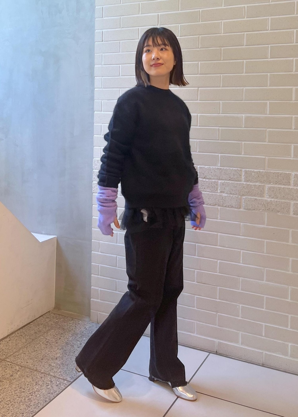 ブラック系のニット/セーター、ブラック系のベスト、グレー系のデニムパンツを着用したレディースの秋コーディネートの5枚目の写真