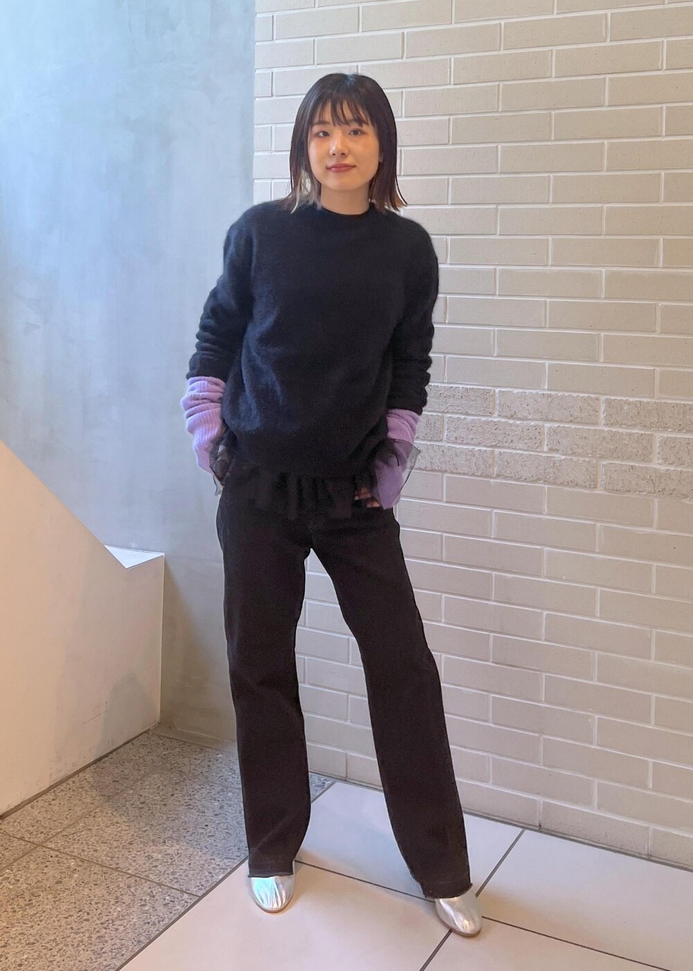 ブラック系のニット/セーター、ブラック系のベスト、グレー系のデニムパンツを着用したレディースの秋コーディネートの2枚目の写真