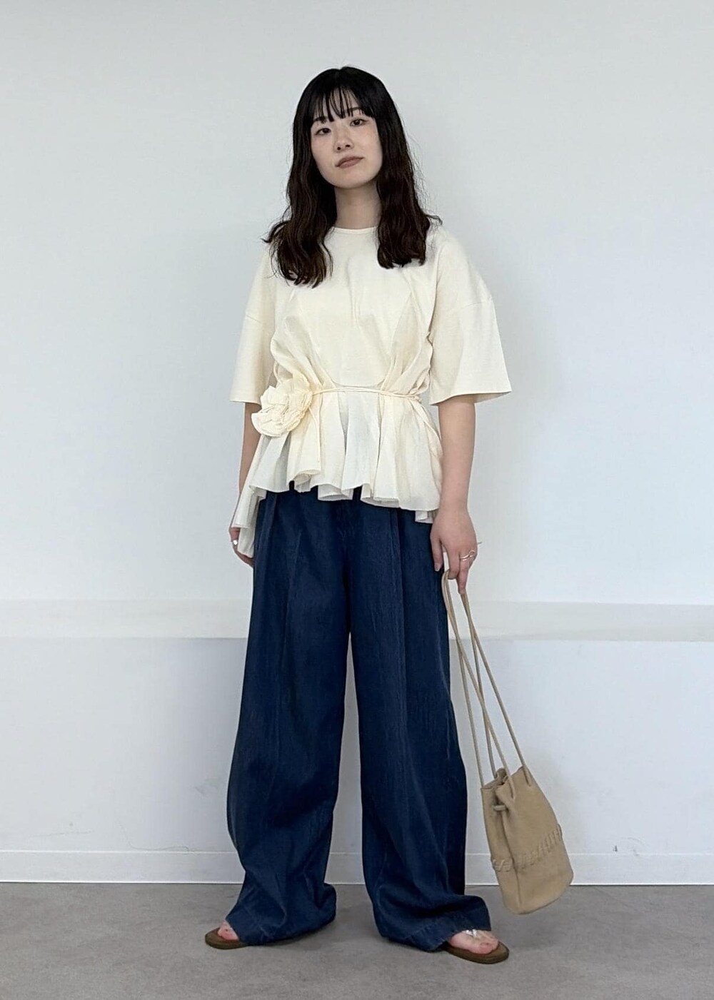 ベージュ系のショルダーバッグ、ブルー系のデニムパンツ、ブラウン系のサンダルを着用したレディースの冬コーディネートの3枚目の写真