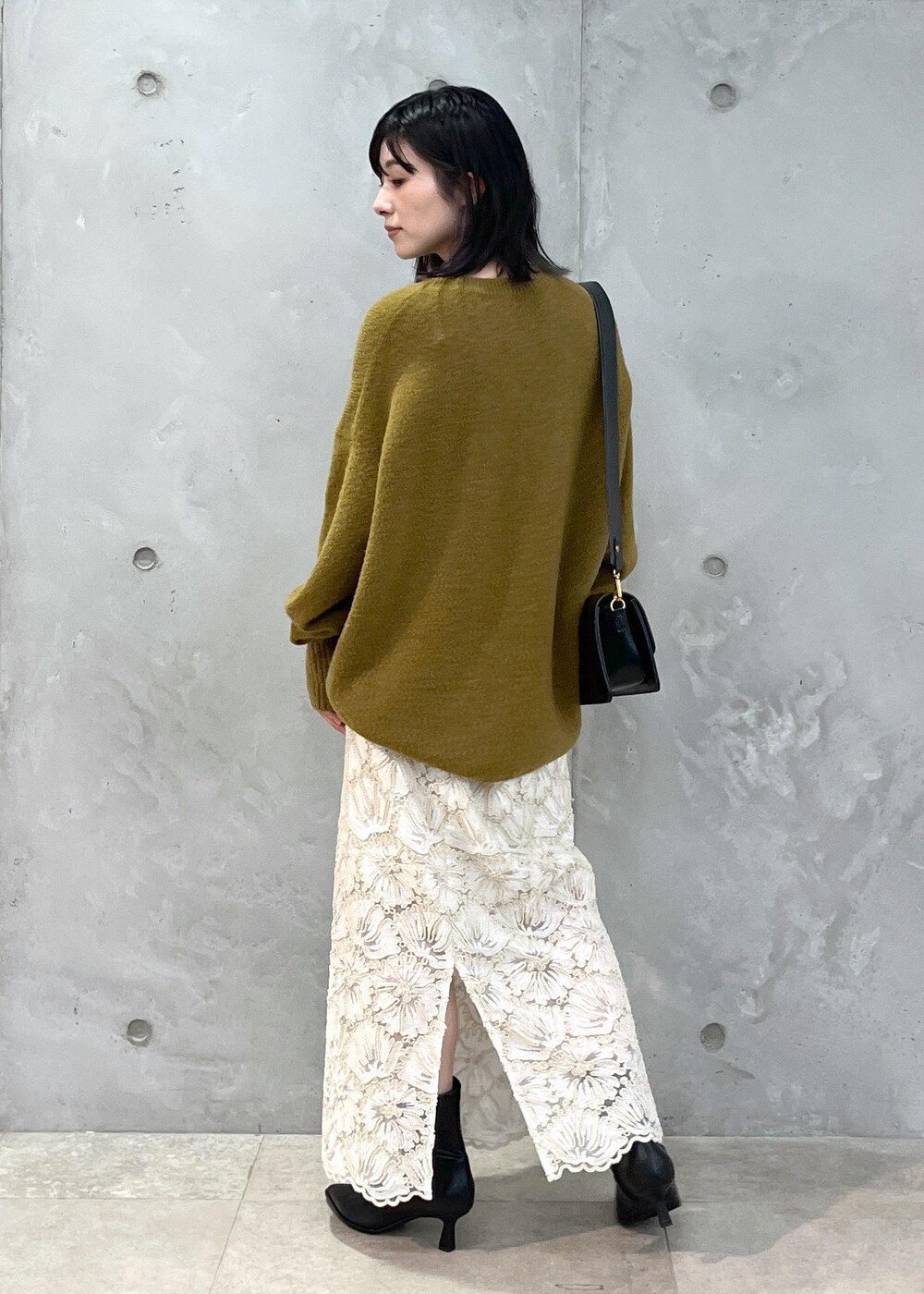 ブラック系のショルダーバッグ、ベージュ系のスカート、イエロー系のニット/セーターを着用したレディースの秋コーディネートの5枚目の写真