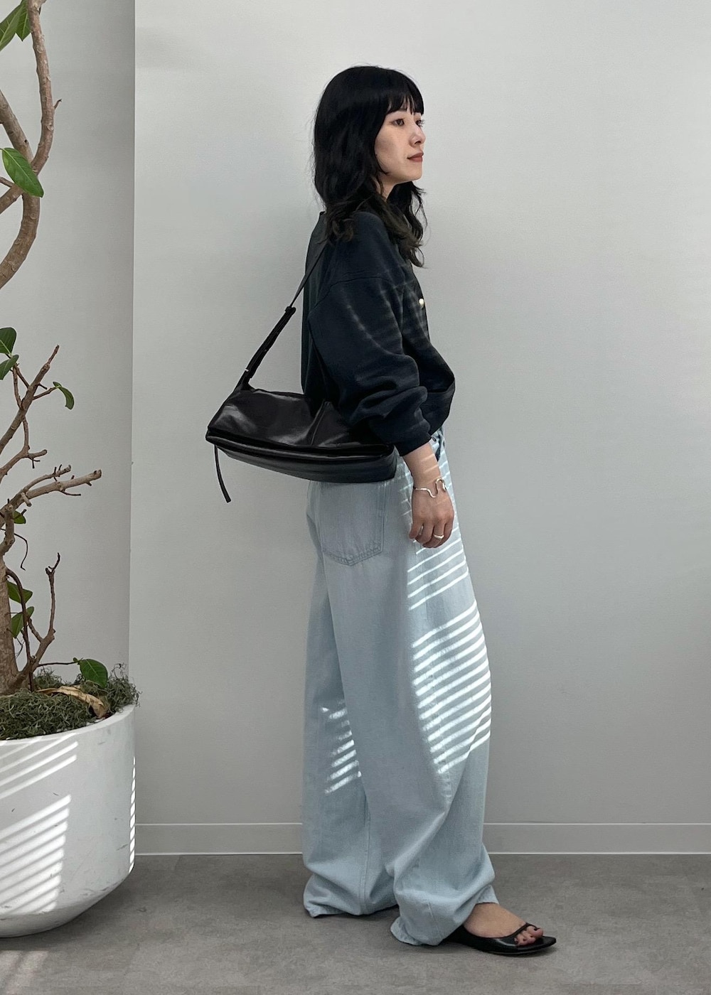 ブルー系のデニムパンツ、グレー系のカーディガン/ボレロ、ブラック系のショルダーバッグを着用したレディースの夏コーディネートの2枚目の写真