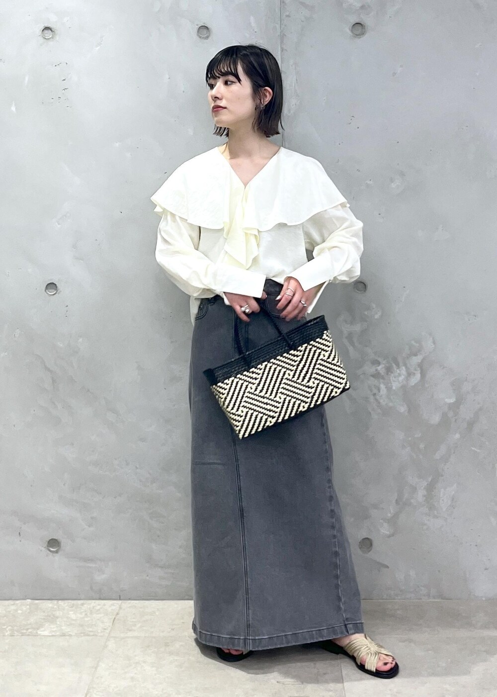 ホワイト系のシャツ/ブラウス、ブラック系のかごバッグ、ゴールド系のサンダルを着用したレディースの春コーディネートの6枚目の写真