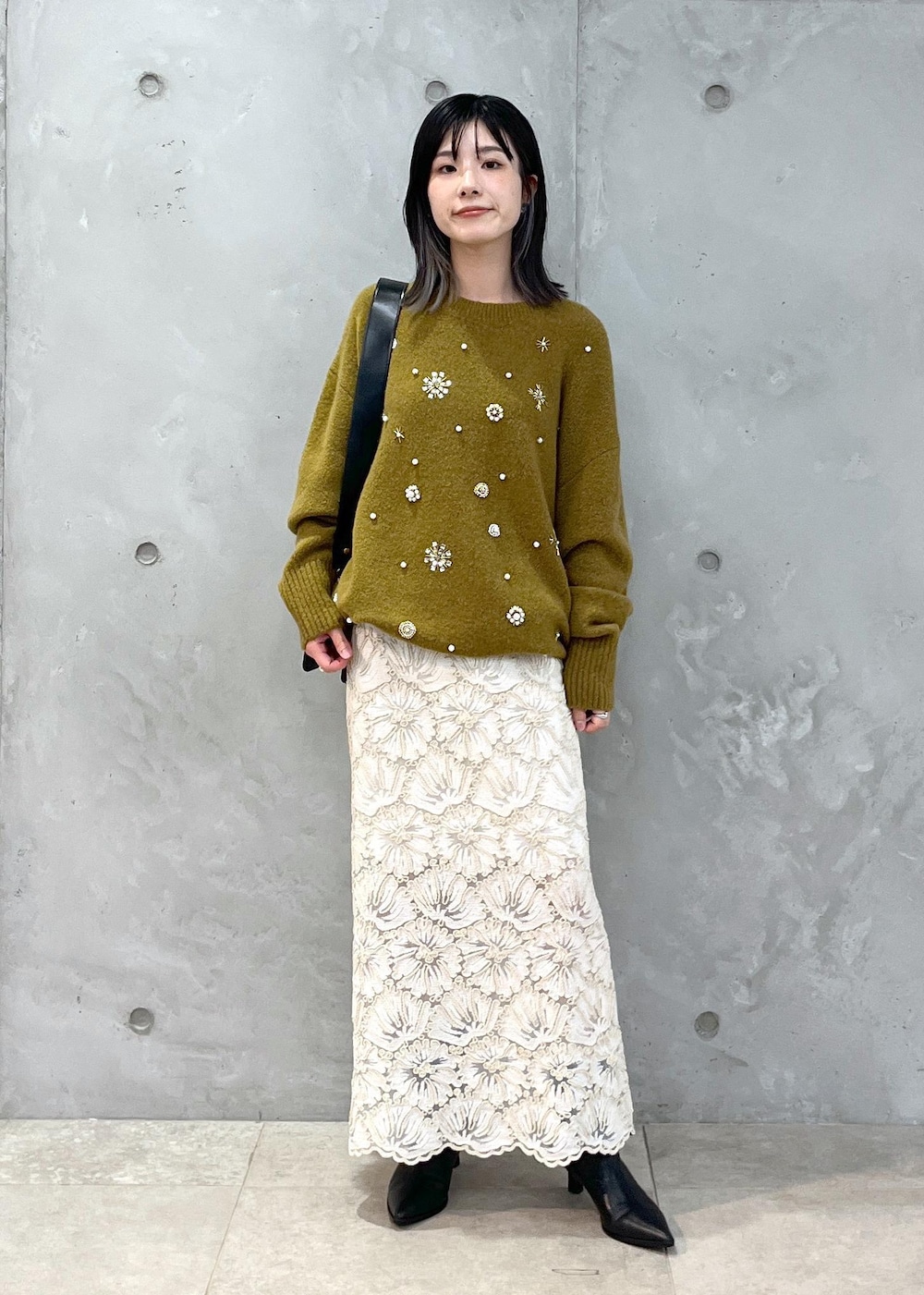 ブラック系のショルダーバッグ、ベージュ系のスカート、イエロー系のニット/セーターを着用したレディースの秋コーディネートの3枚目の写真