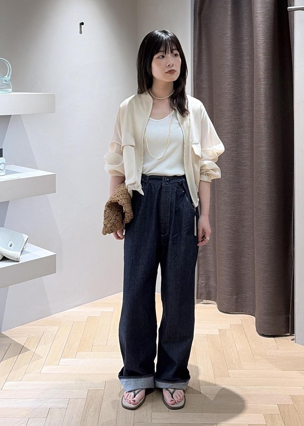 ベージュ系のサンダル、ブラウン系のハンドバッグ、ブルー系のデニムパンツを着用したレディースの夏コーディネートの2枚目の写真