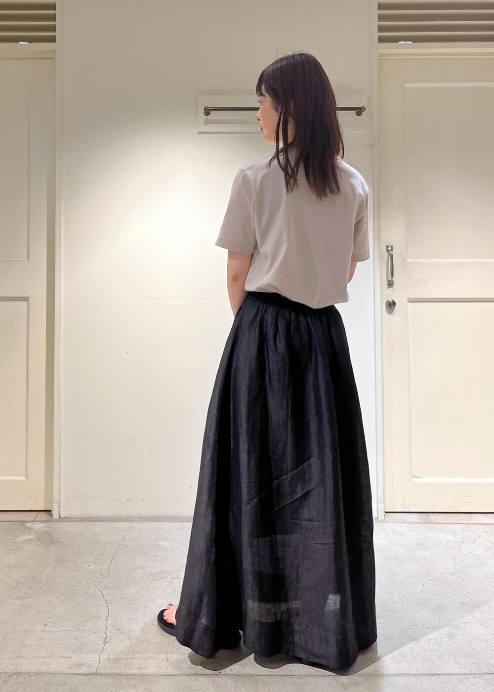 ブラック系のスカート、ベージュ系のTシャツ/カットソーを着用したレディースの夏コーディネートの4枚目の写真