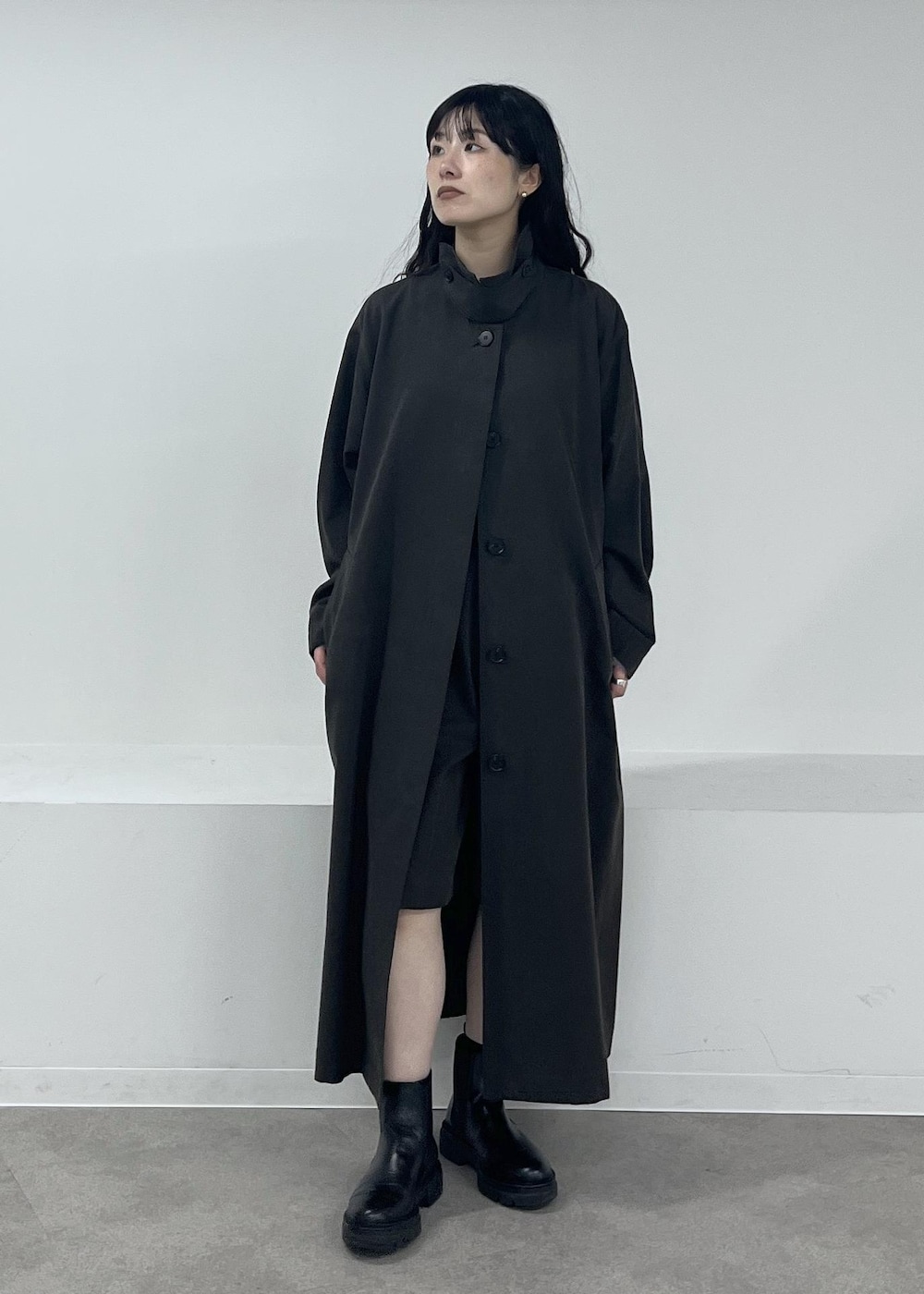 ブルー系のニット/セーター、グレー系のステンカラーコート、グレー系のその他パンツを着用したレディースの冬コーディネートの2枚目の写真