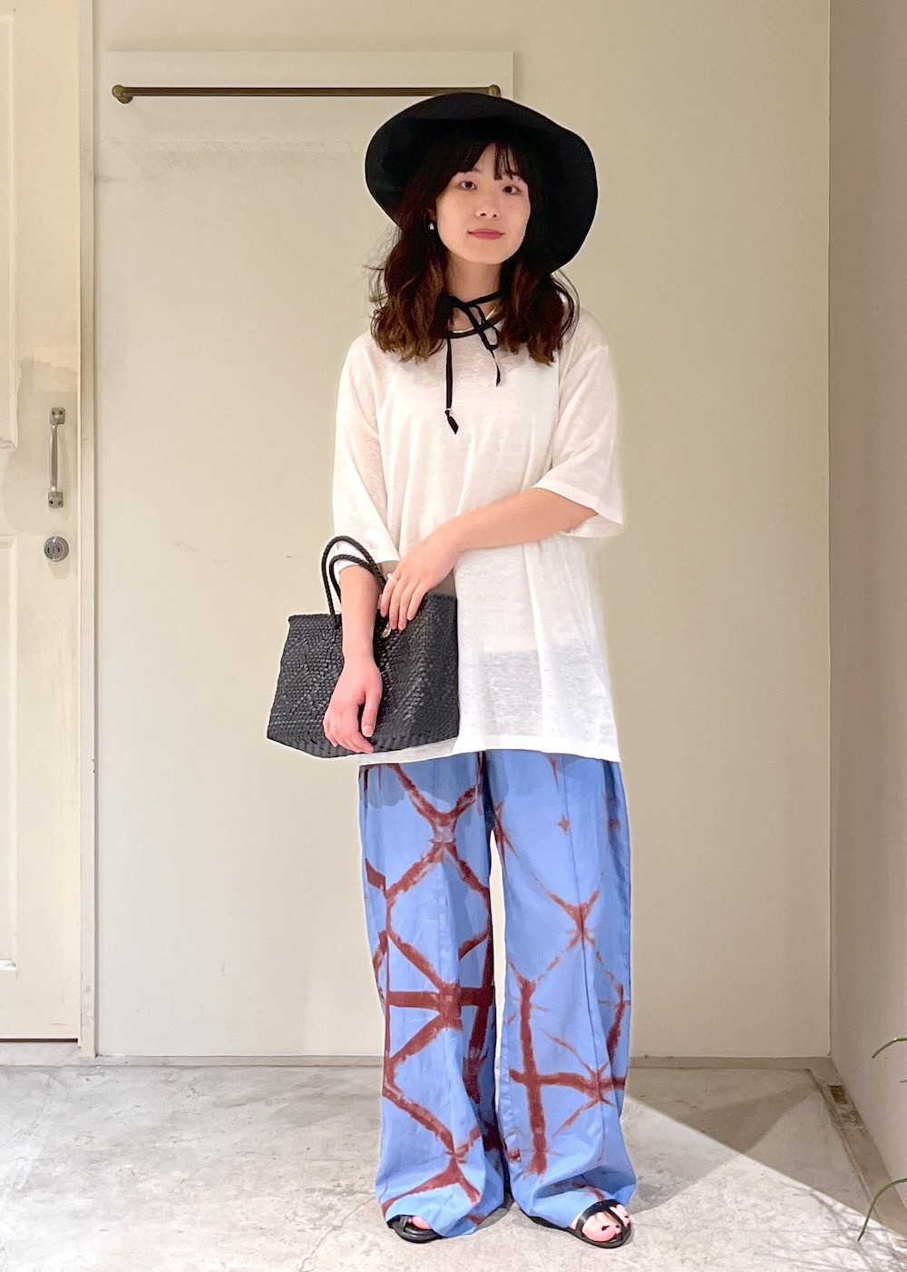 ブラック系のかごバッグ、ブラック系のサンダル、ブルー系のその他パンツを着用したレディースの春コーディネートの4枚目の写真