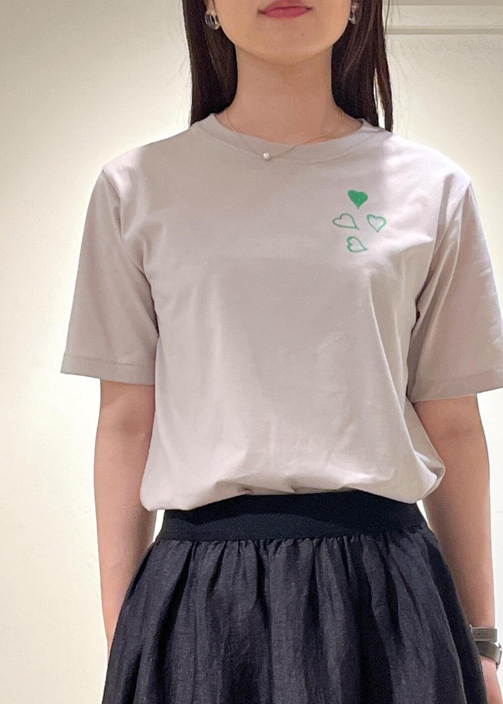 ブラック系のスカート、ベージュ系のTシャツ/カットソーを着用したレディースの夏コーディネートの5枚目の写真