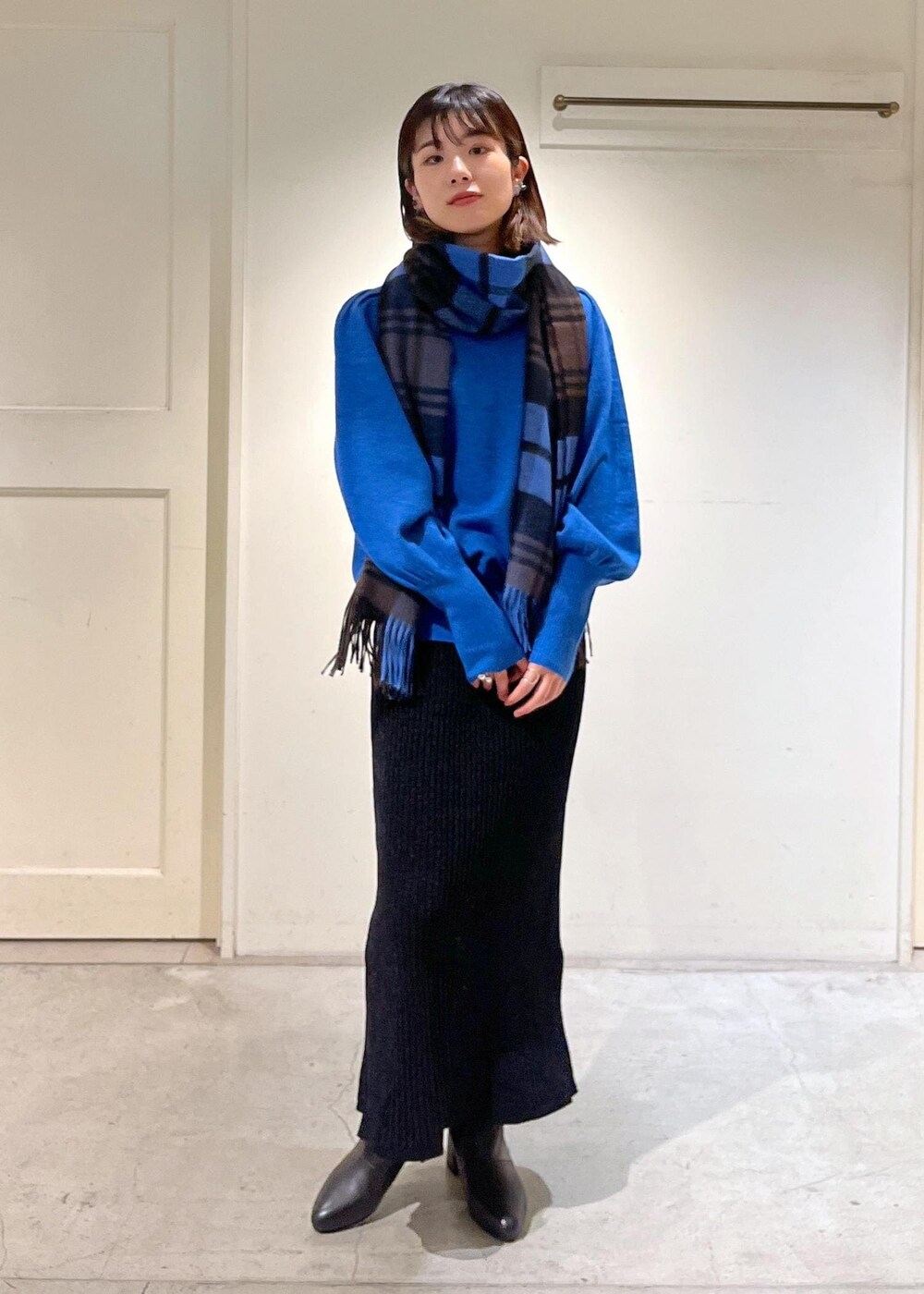 ブラック系のブーツ、ブラック系のスカート、ブルー系のニット/セーターを着用したレディースの秋コーディネートの4枚目の写真