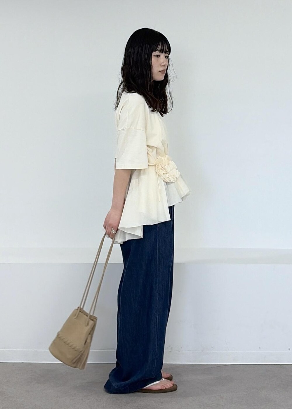 ベージュ系のショルダーバッグ、ブルー系のデニムパンツ、ブラウン系のサンダルを着用したレディースの冬コーディネートの4枚目の写真