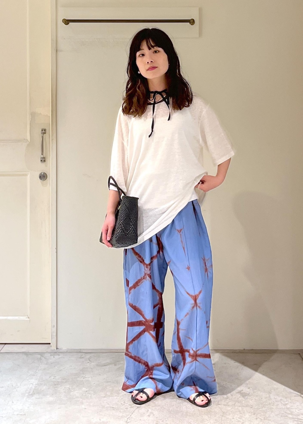 ブラック系のかごバッグ、ブラック系のサンダル、ブルー系のその他パンツを着用したレディースの春コーディネートの2枚目の写真