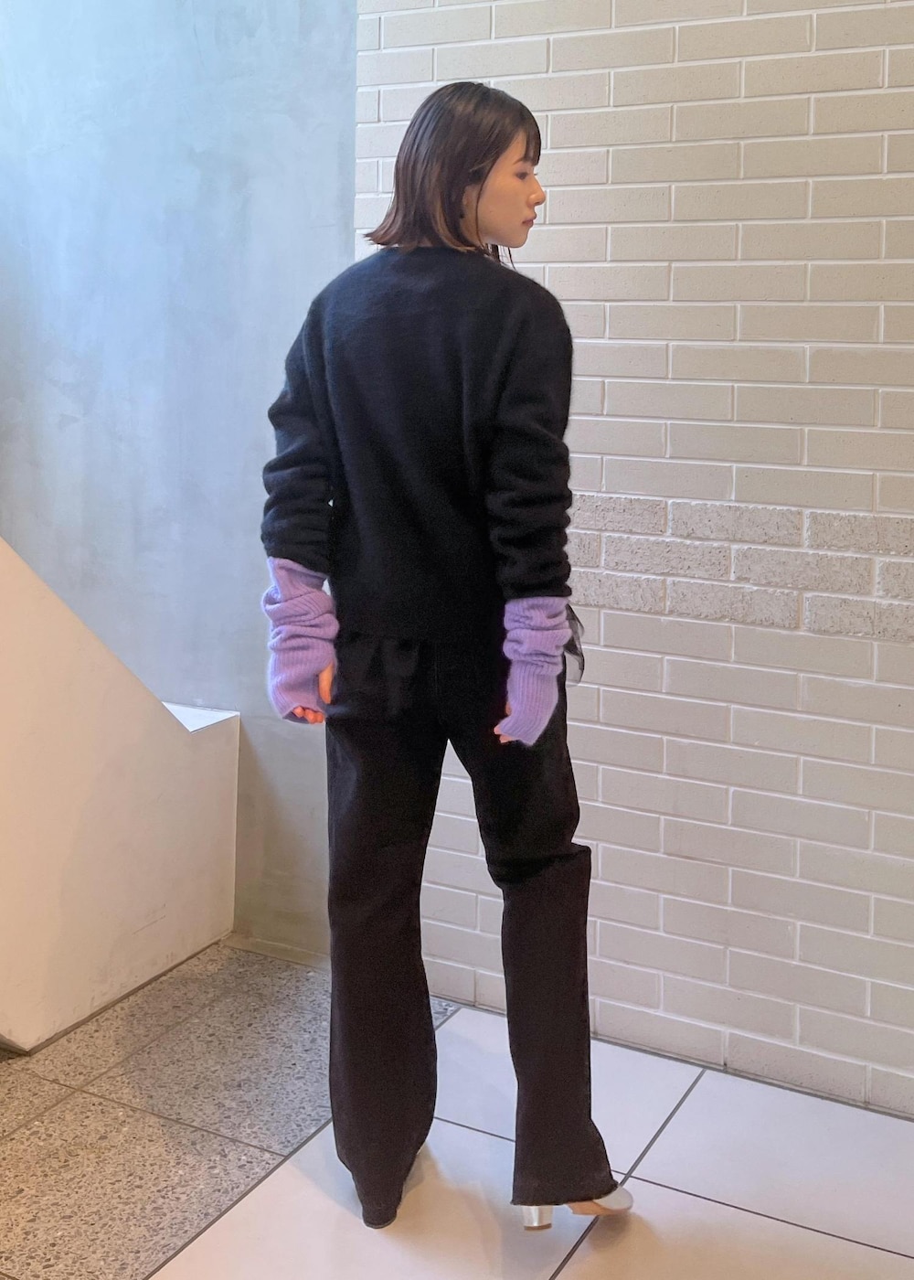 ブラック系のニット/セーター、ブラック系のベスト、グレー系のデニムパンツを着用したレディースの秋コーディネートの7枚目の写真