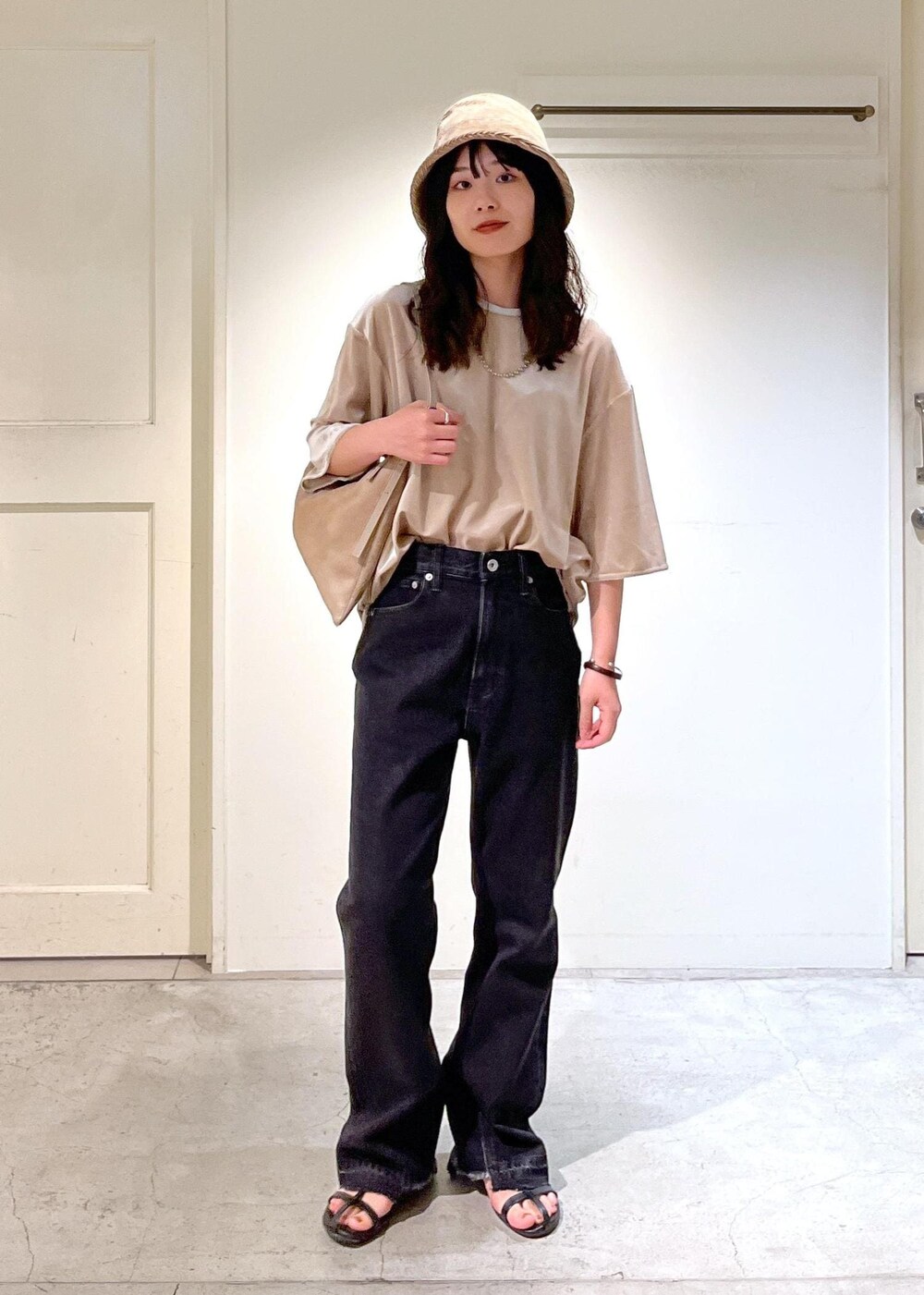 ブラック系のサンダル、グレー系のデニムパンツ、ベージュ系のTシャツ/カットソーを着用したレディースの夏コーディネートの2枚目の写真