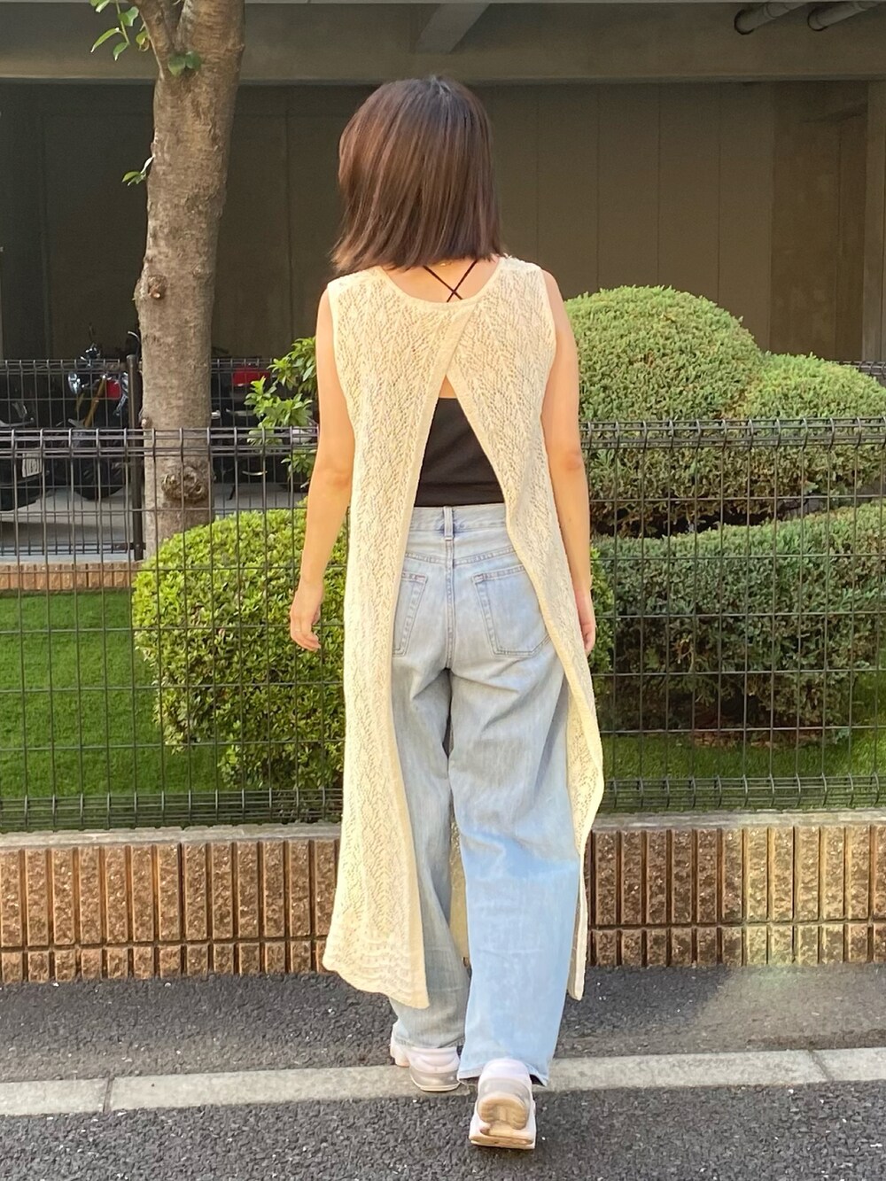 ホワイト系のサンダル、ブルー系のデニムパンツ、ブラック系のキャミソールを着用したレディースの秋コーディネートの2枚目の写真