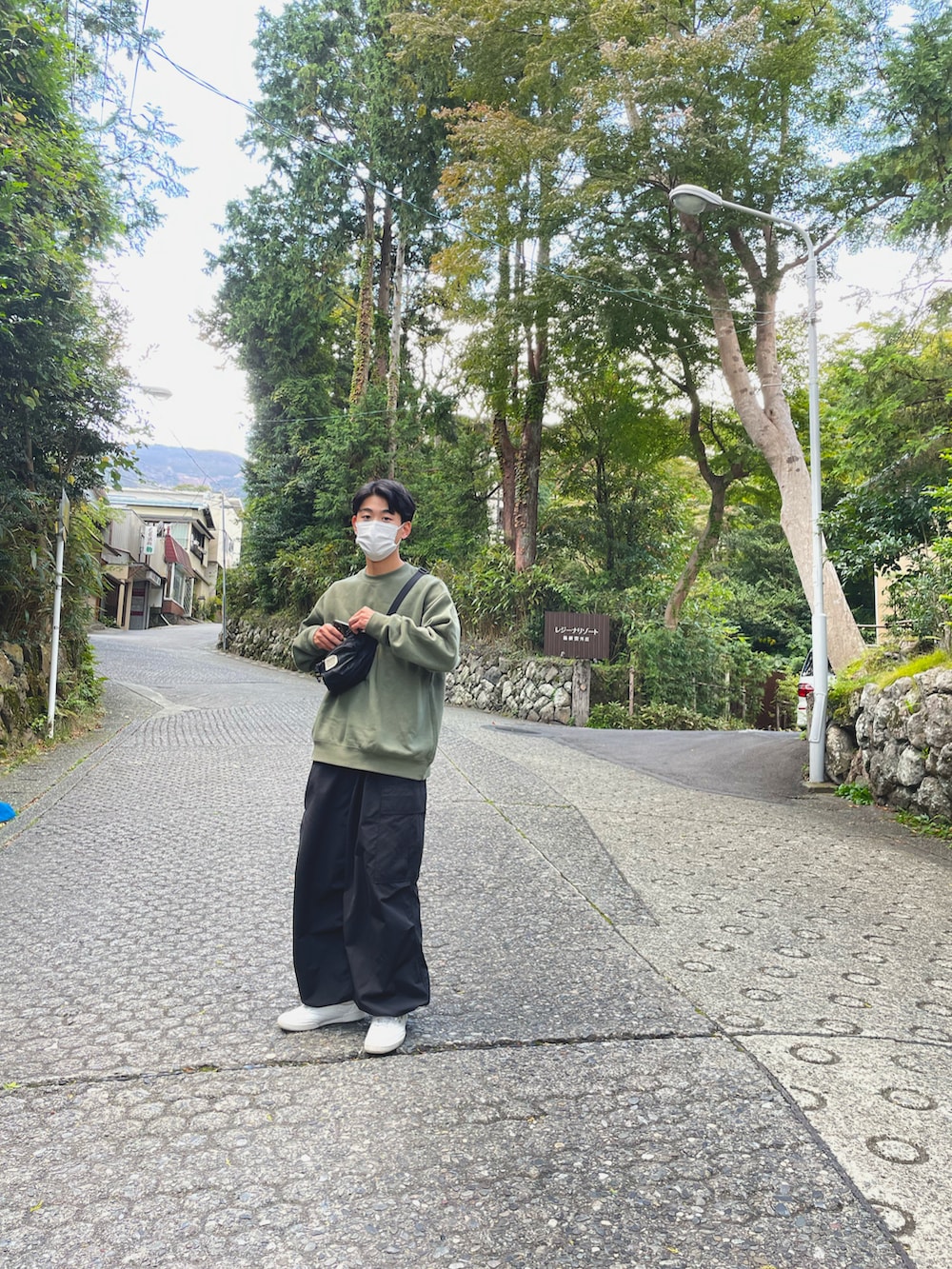 グリーン系のスウェット、ブラック系のボディバッグ/ウエストポーチ、ブラック系のカーゴパンツを着用したメンズの秋コーディネートの2枚目の写真