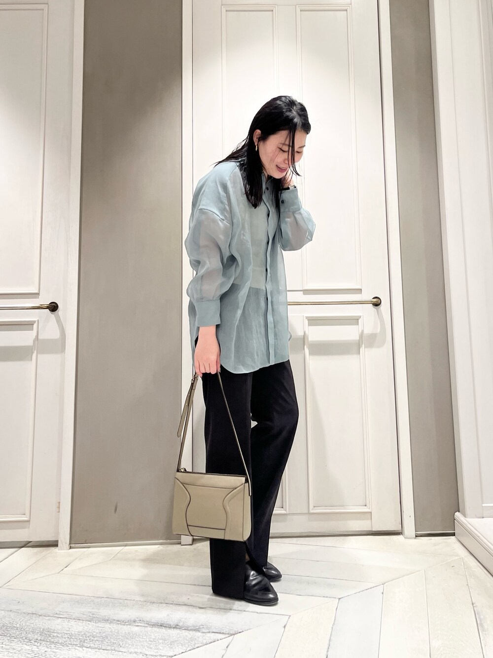 ブルー系のシャツ/ブラウス、ブラック系のスラックス、ベージュ系のショルダーバッグを着用したレディースの春コーディネートの2枚目の写真