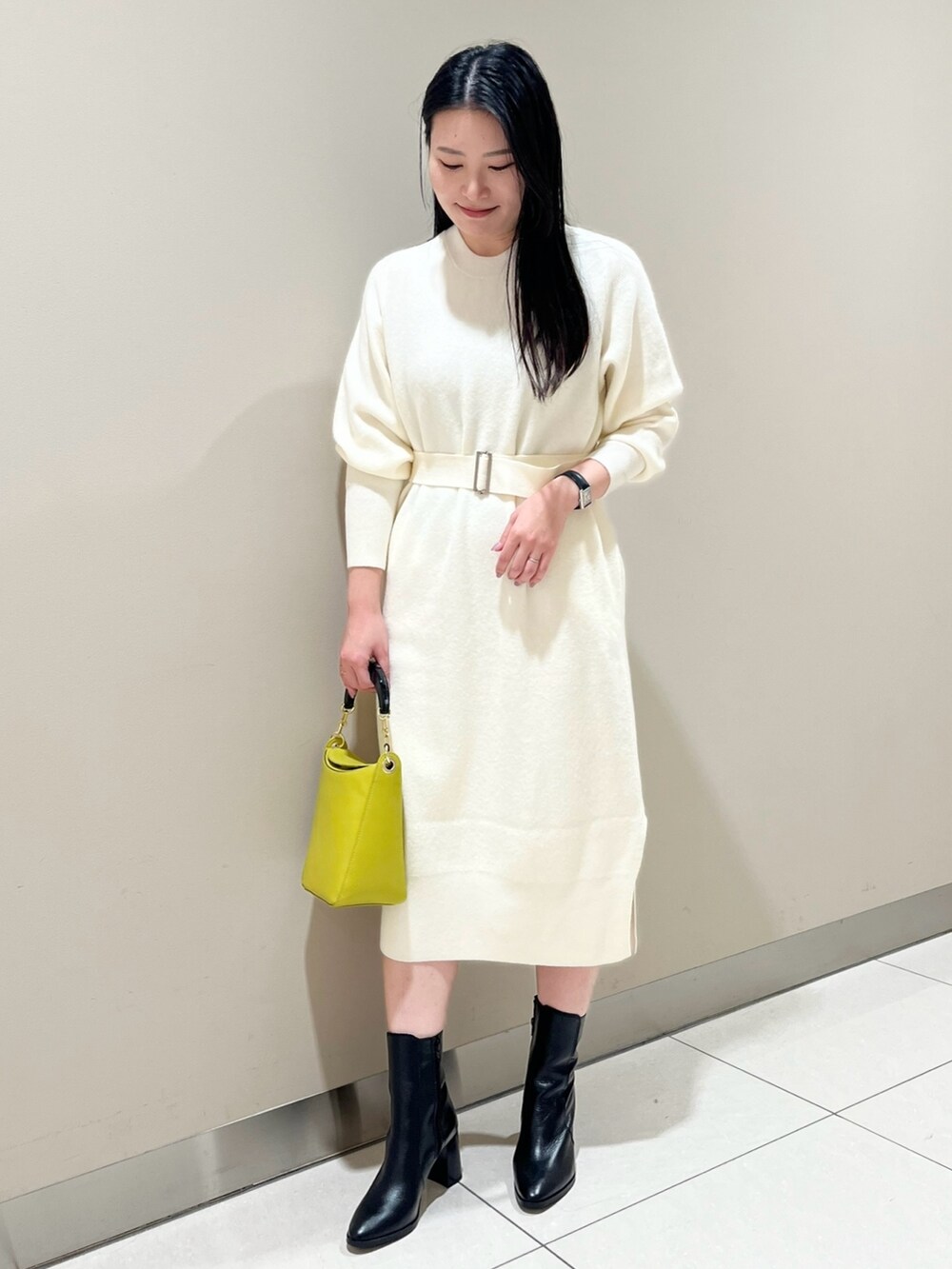 ホワイト系のワンピース、イエロー系のハンドバッグ、ブラック系のブーツを着用したレディースの冬コーディネートの2枚目の写真