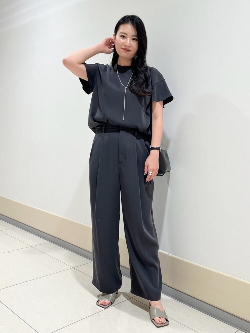 グレー系のシャツ/ブラウス、グレー系のスラックス、ブラック系のショルダーバッグを着用したレディースの春コーディネートの3枚目の写真