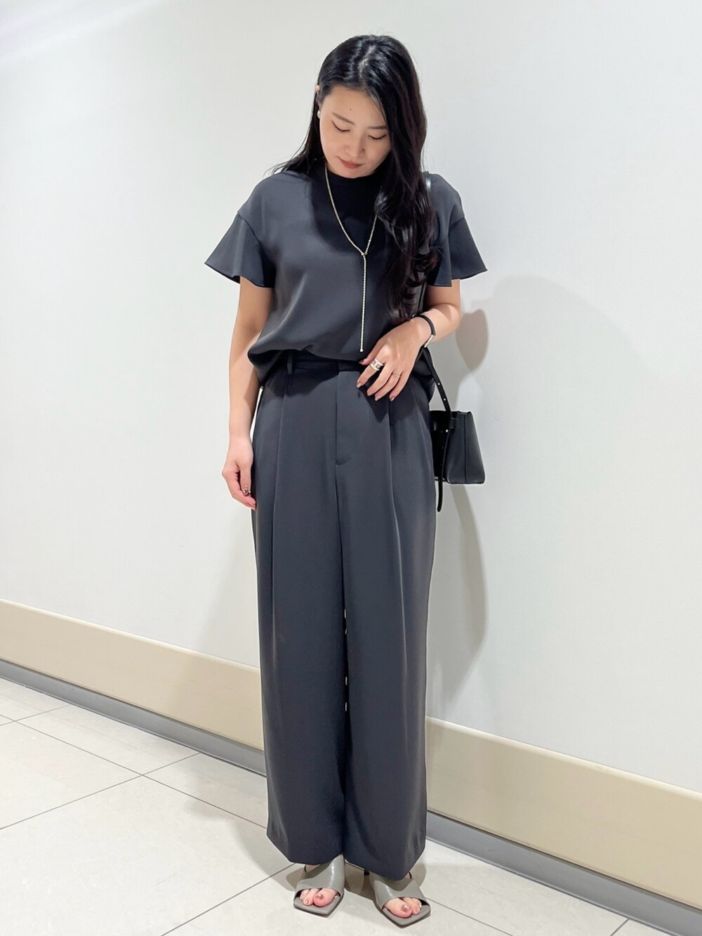 グレー系のシャツ/ブラウス、グレー系のスラックス、ブラック系のショルダーバッグを着用したレディースの春コーディネートの4枚目の写真