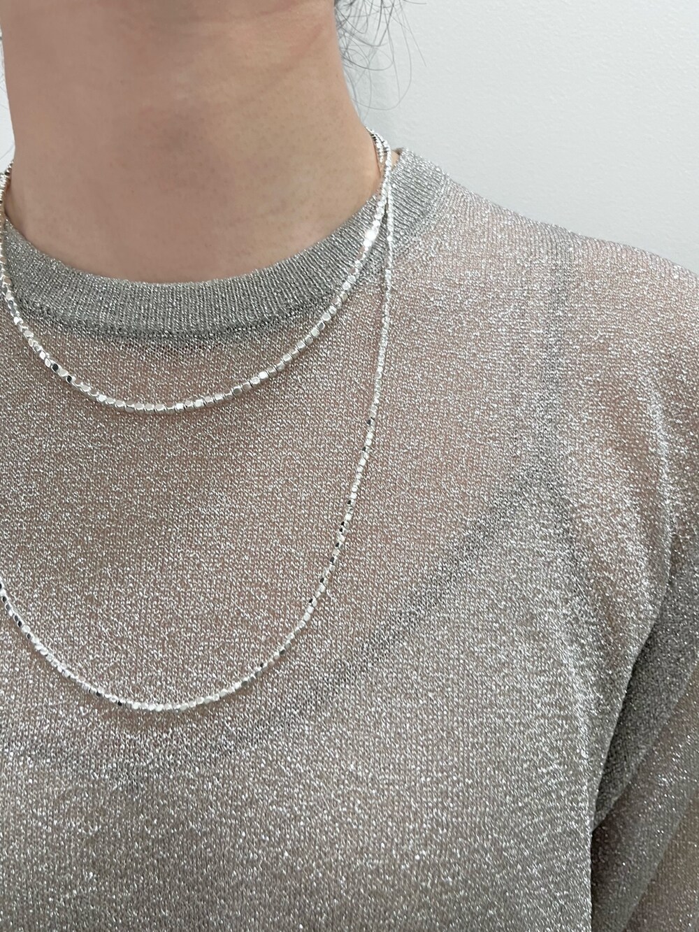 シルバー系のニット/セーター、グリーン系のスラックス、ブラック系のトートバッグを着用したレディースの夏コーディネートの4枚目の写真