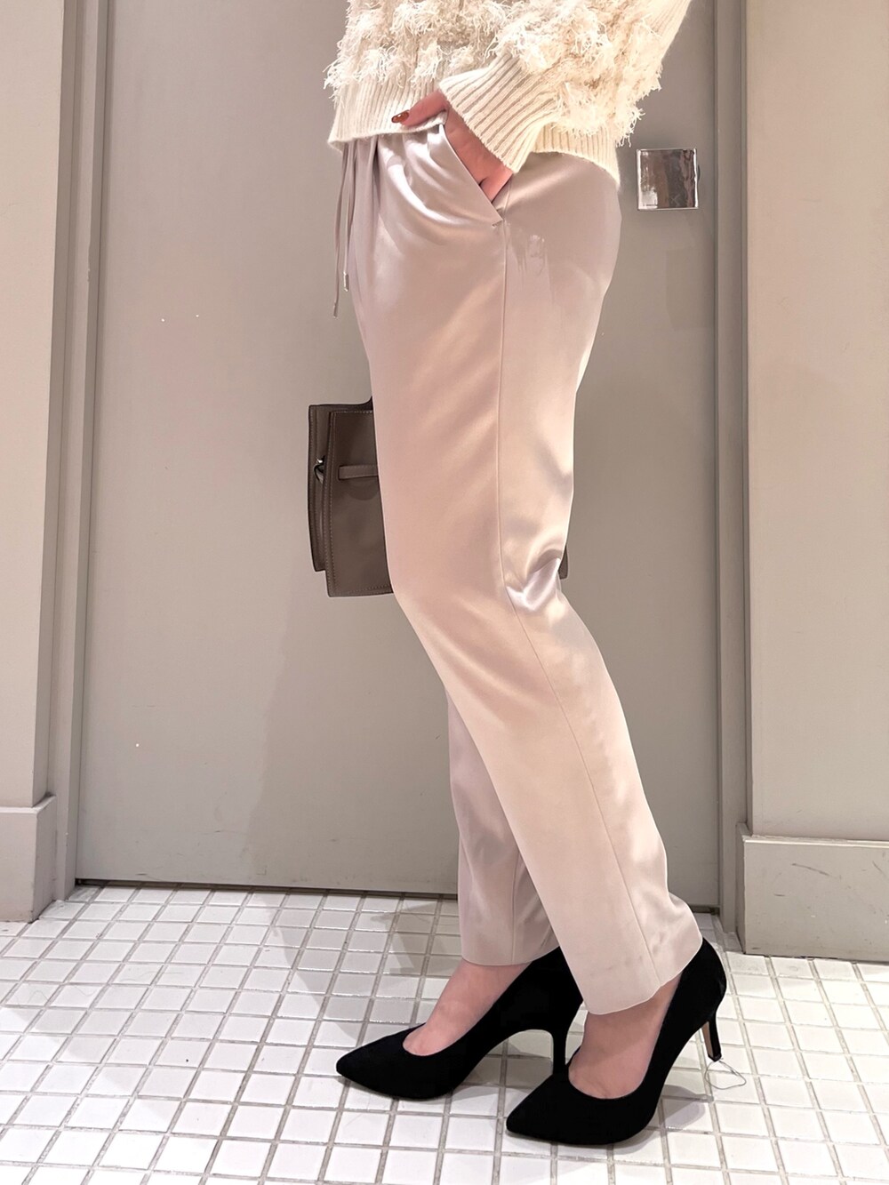 ホワイト系のニット/セーター、ベージュ系のスラックス、ベージュ系のトートバッグを着用したレディースの秋コーディネートの6枚目の写真