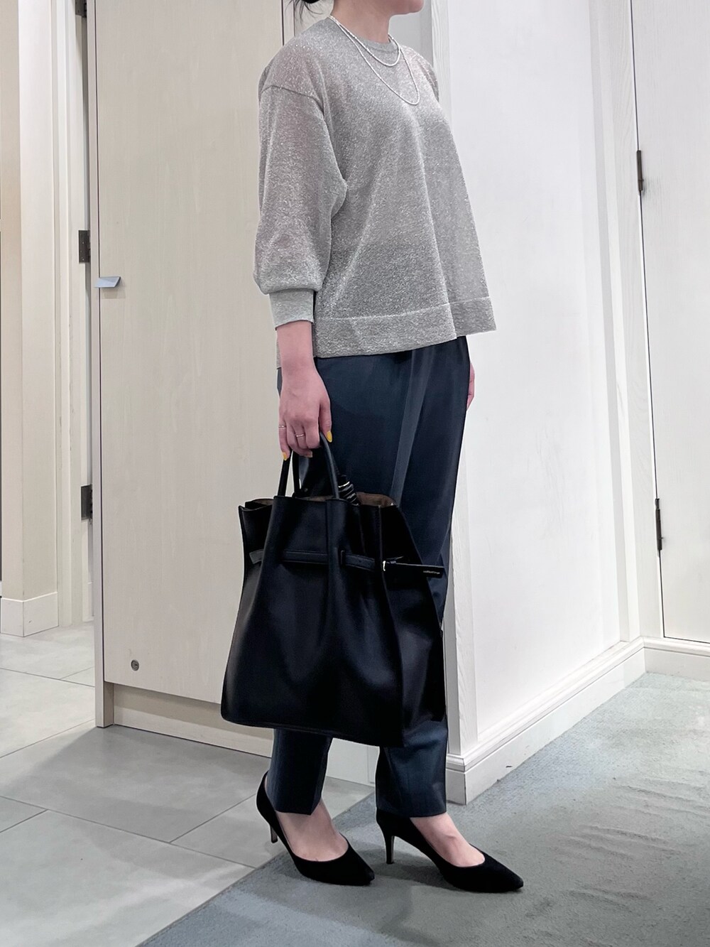 シルバー系のニット/セーター、グリーン系のスラックス、ブラック系のトートバッグを着用したレディースの夏コーディネートの2枚目の写真