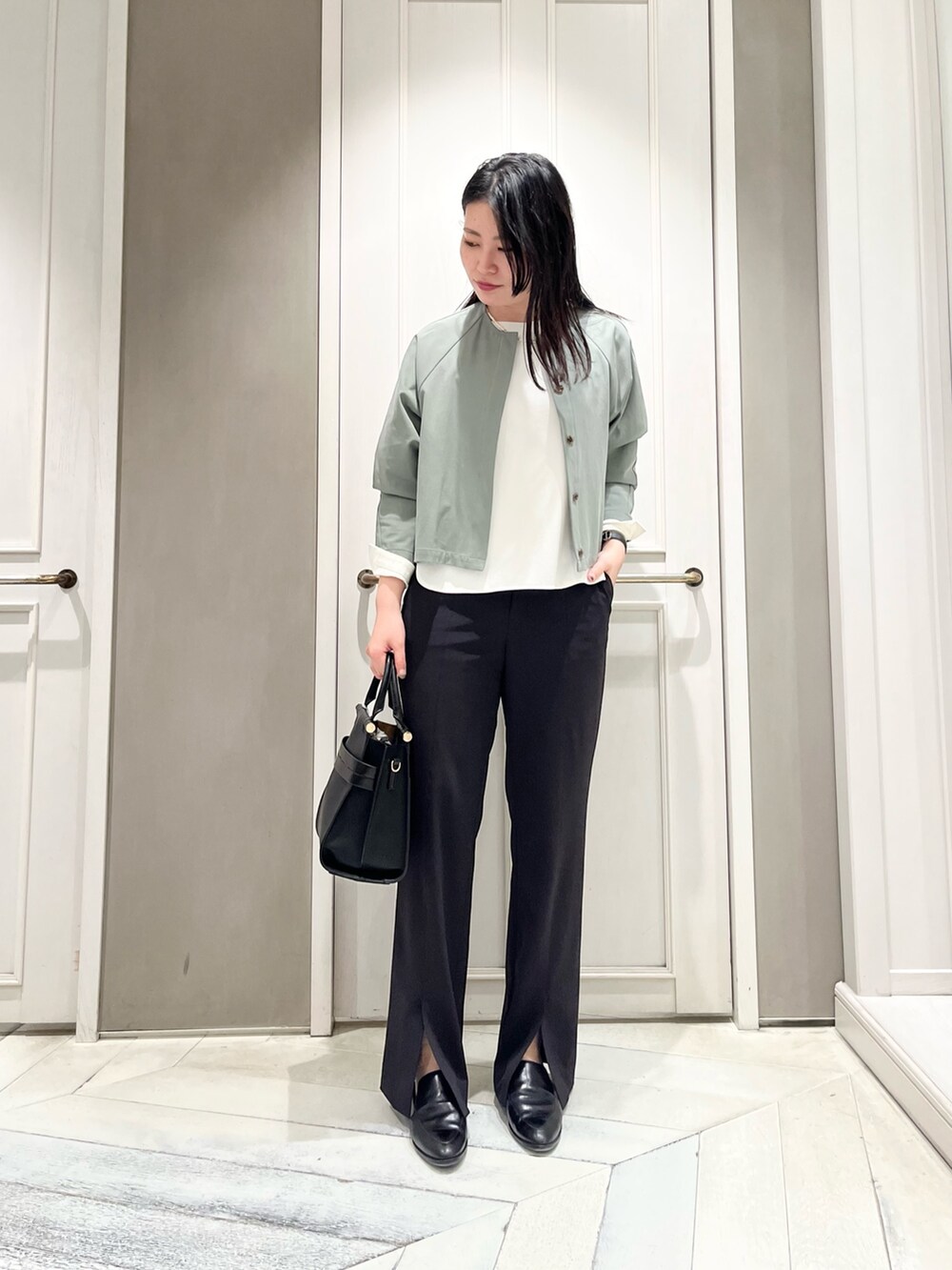 グリーン系のシャツ/ブラウス、ホワイト系のシャツ/ブラウス、ブラック系のスラックスを着用したレディースの春コーディネートの2枚目の写真