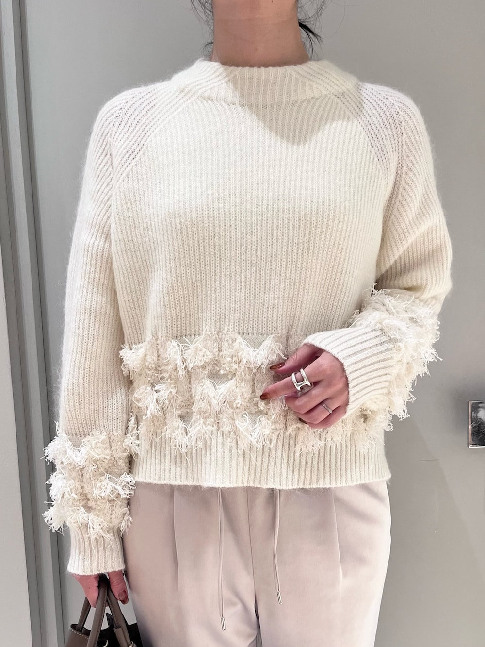 ホワイト系のニット/セーター、ベージュ系のスラックス、ベージュ系のトートバッグを着用したレディースの秋コーディネートの3枚目の写真