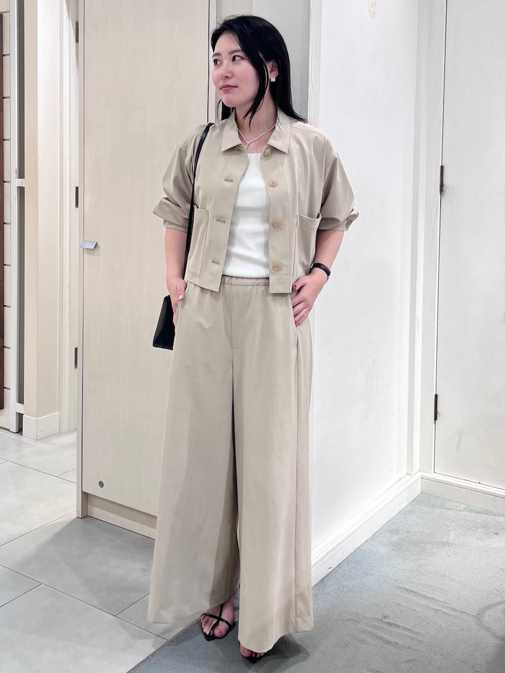 ベージュ系のブルゾン、ベージュ系のその他パンツ、ホワイト系のタンクトップを着用したレディースの春コーディネートの2枚目の写真