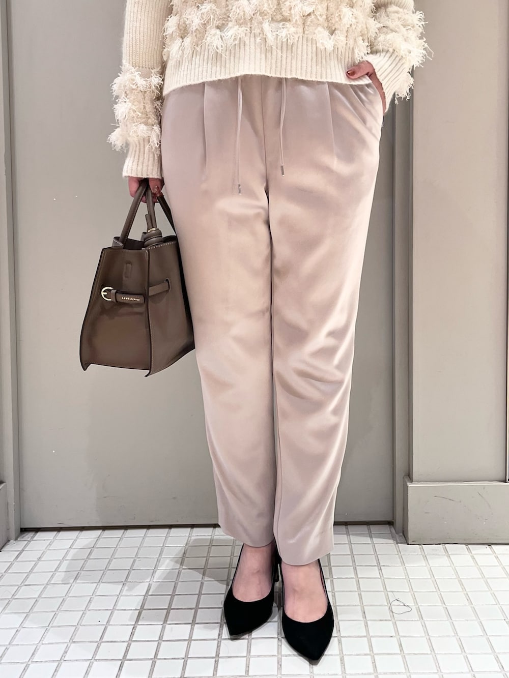 ホワイト系のニット/セーター、ベージュ系のスラックス、ベージュ系のトートバッグを着用したレディースの秋コーディネートの5枚目の写真