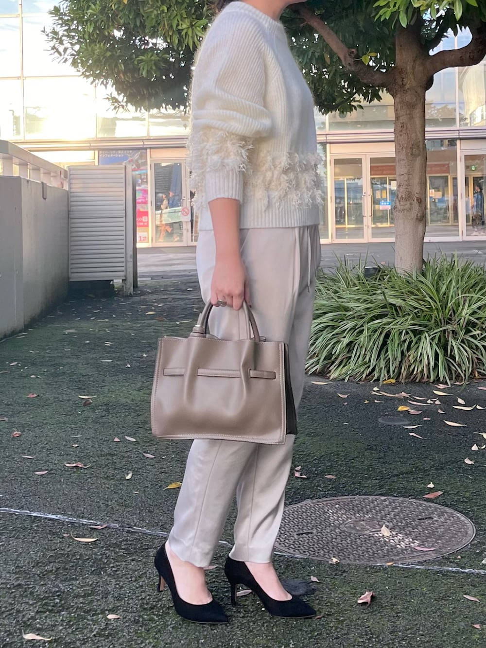ホワイト系のニット/セーター、ベージュ系のスラックス、ベージュ系のトートバッグを着用したレディースの秋コーディネートの2枚目の写真