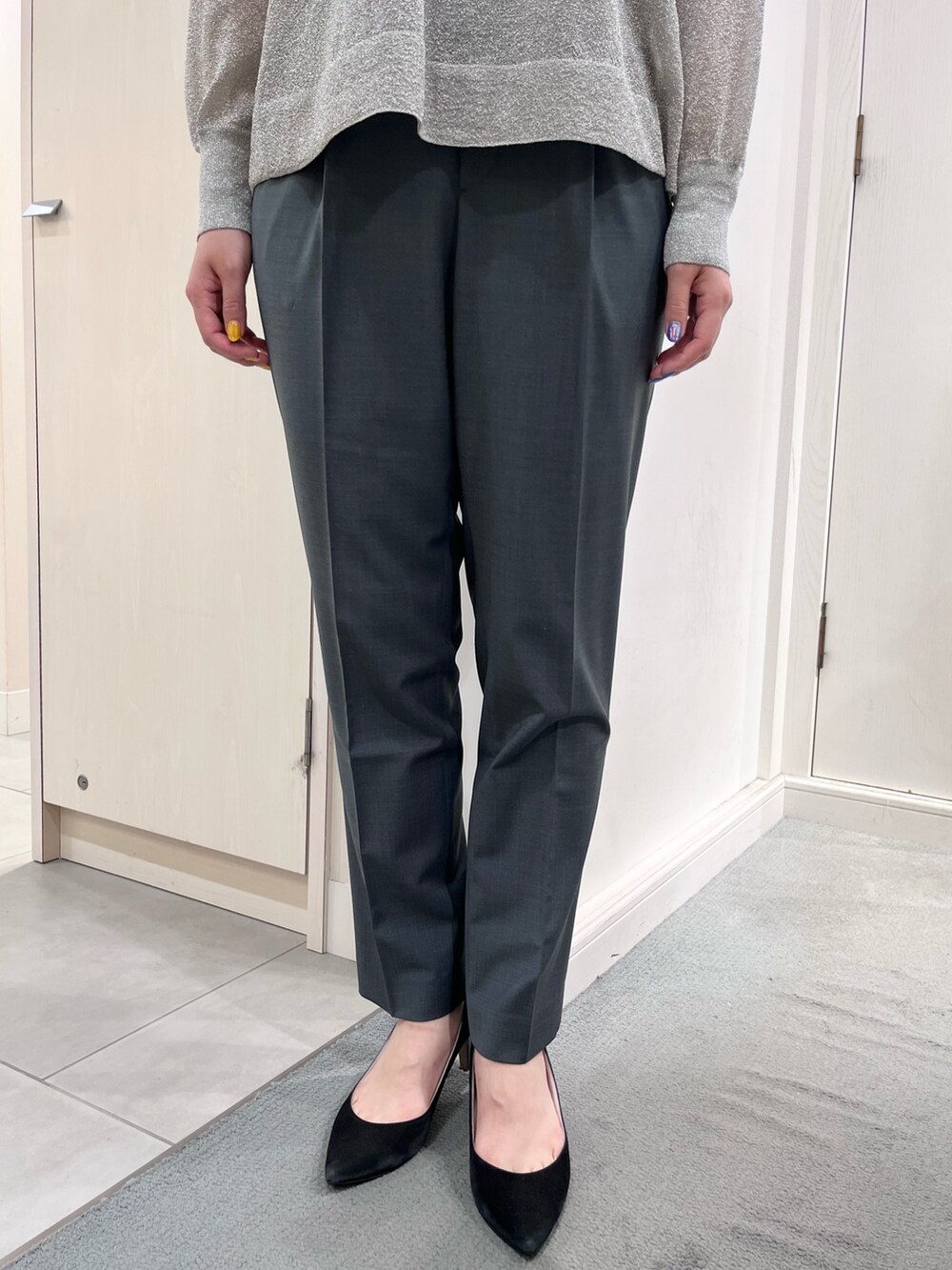 シルバー系のニット/セーター、グリーン系のスラックス、ブラック系のトートバッグを着用したレディースの夏コーディネートの6枚目の写真