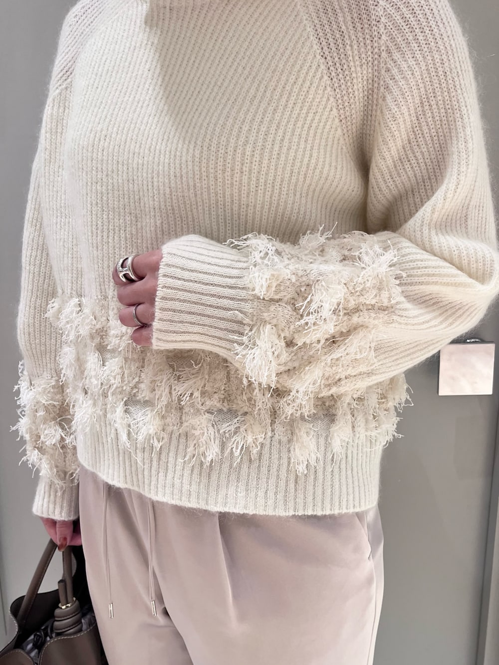 ホワイト系のニット/セーター、ベージュ系のスラックス、ベージュ系のトートバッグを着用したレディースの秋コーディネートの4枚目の写真