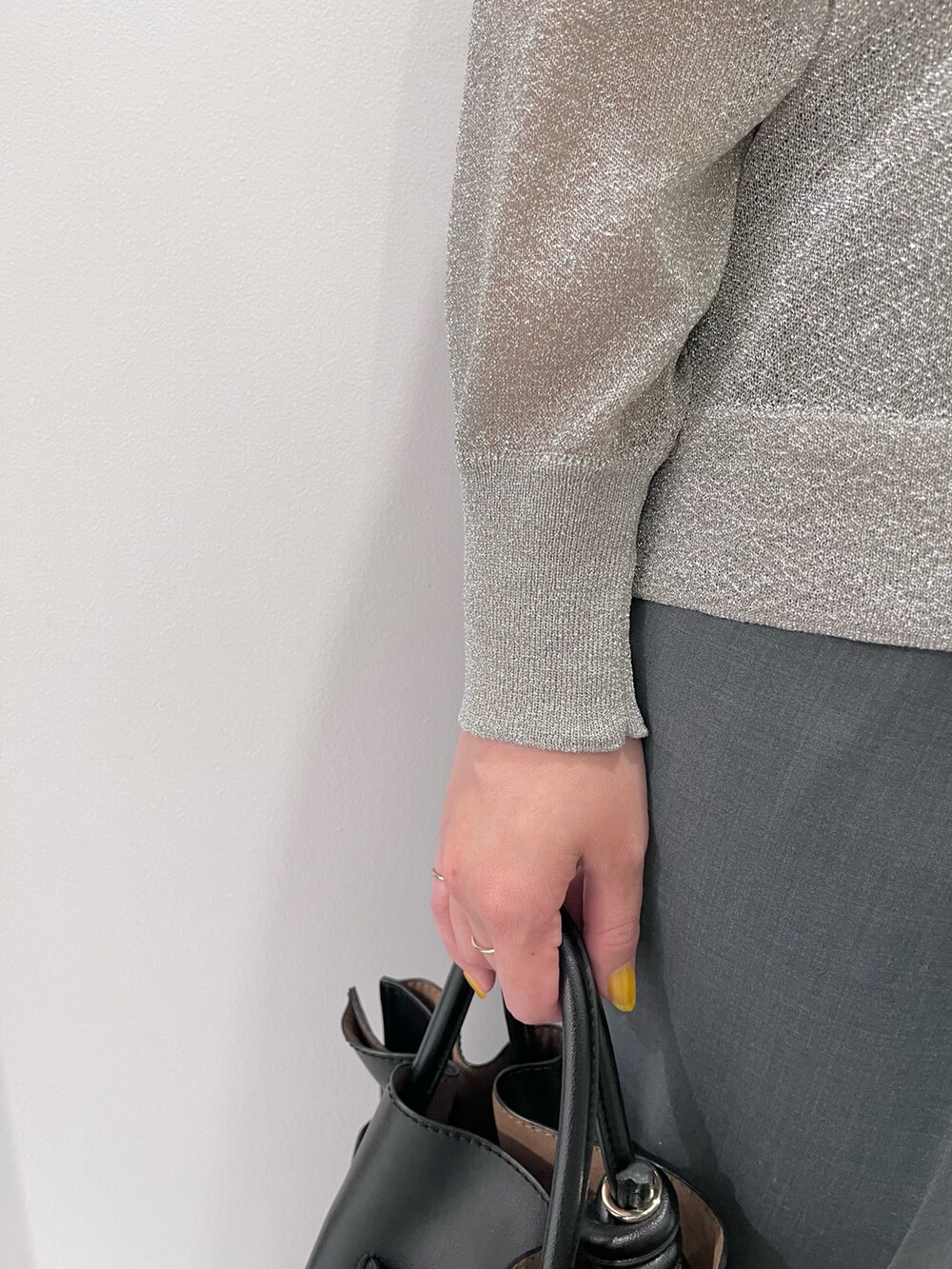 シルバー系のニット/セーター、グリーン系のスラックス、ブラック系のトートバッグを着用したレディースの夏コーディネートの5枚目の写真