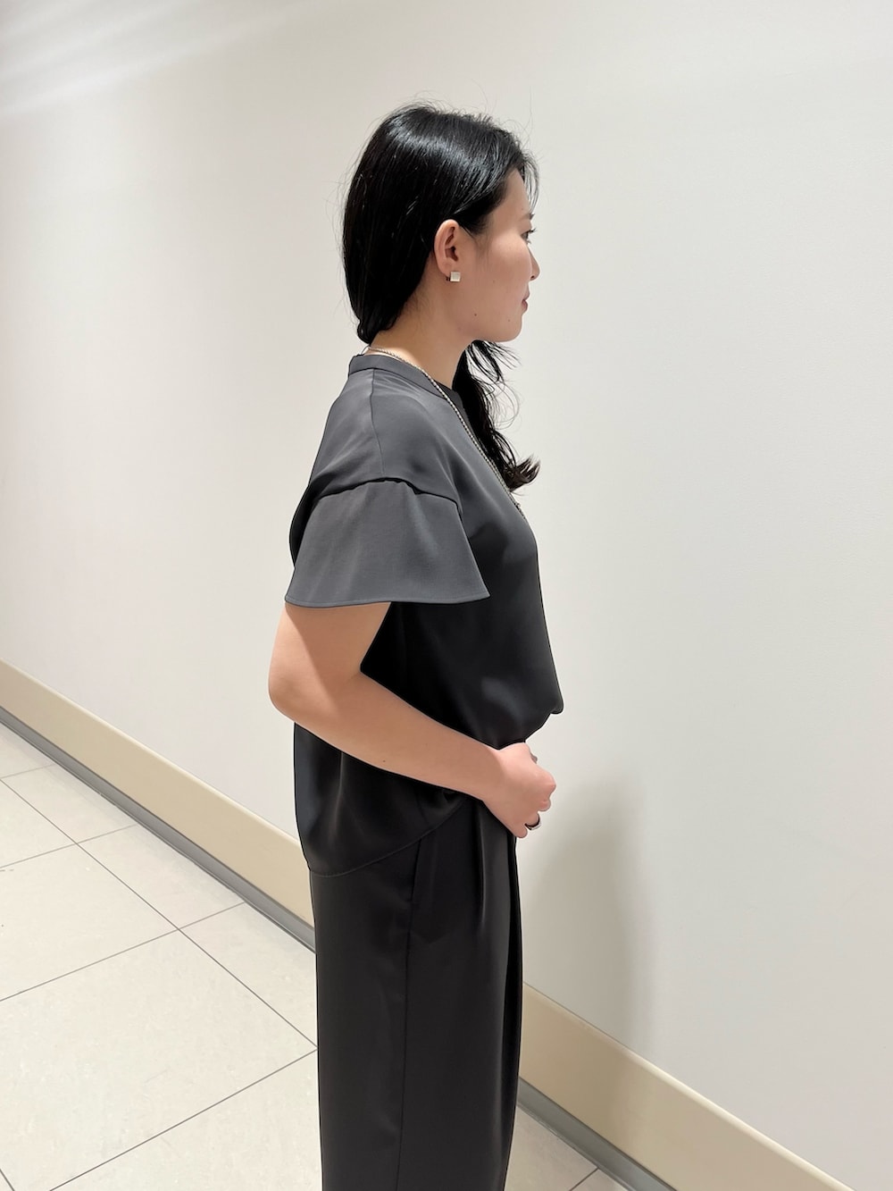 グレー系のシャツ/ブラウス、グレー系のスラックス、ブラック系のショルダーバッグを着用したレディースの春コーディネートの5枚目の写真