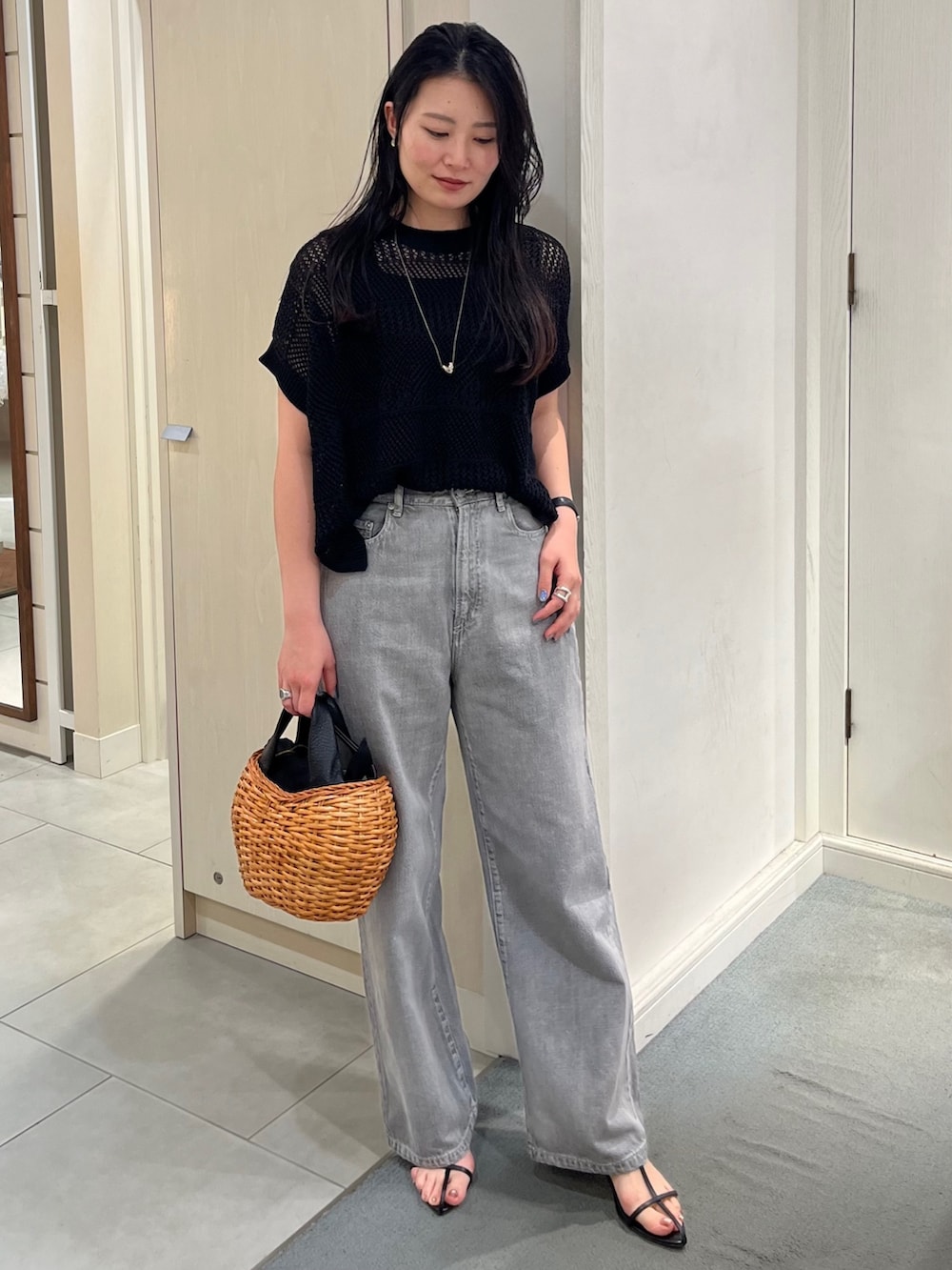 ブラック系のニット/セーター、ブラック系のデニムパンツ、ブラック系のトートバッグを着用したレディースの春コーディネートの2枚目の写真