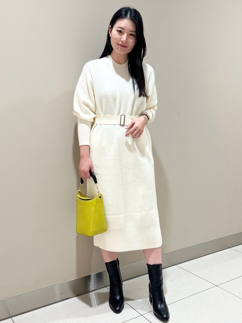 ホワイト系のワンピース、イエロー系のハンドバッグ、ブラック系のブーツを着用したレディースの冬コーディネートの3枚目の写真