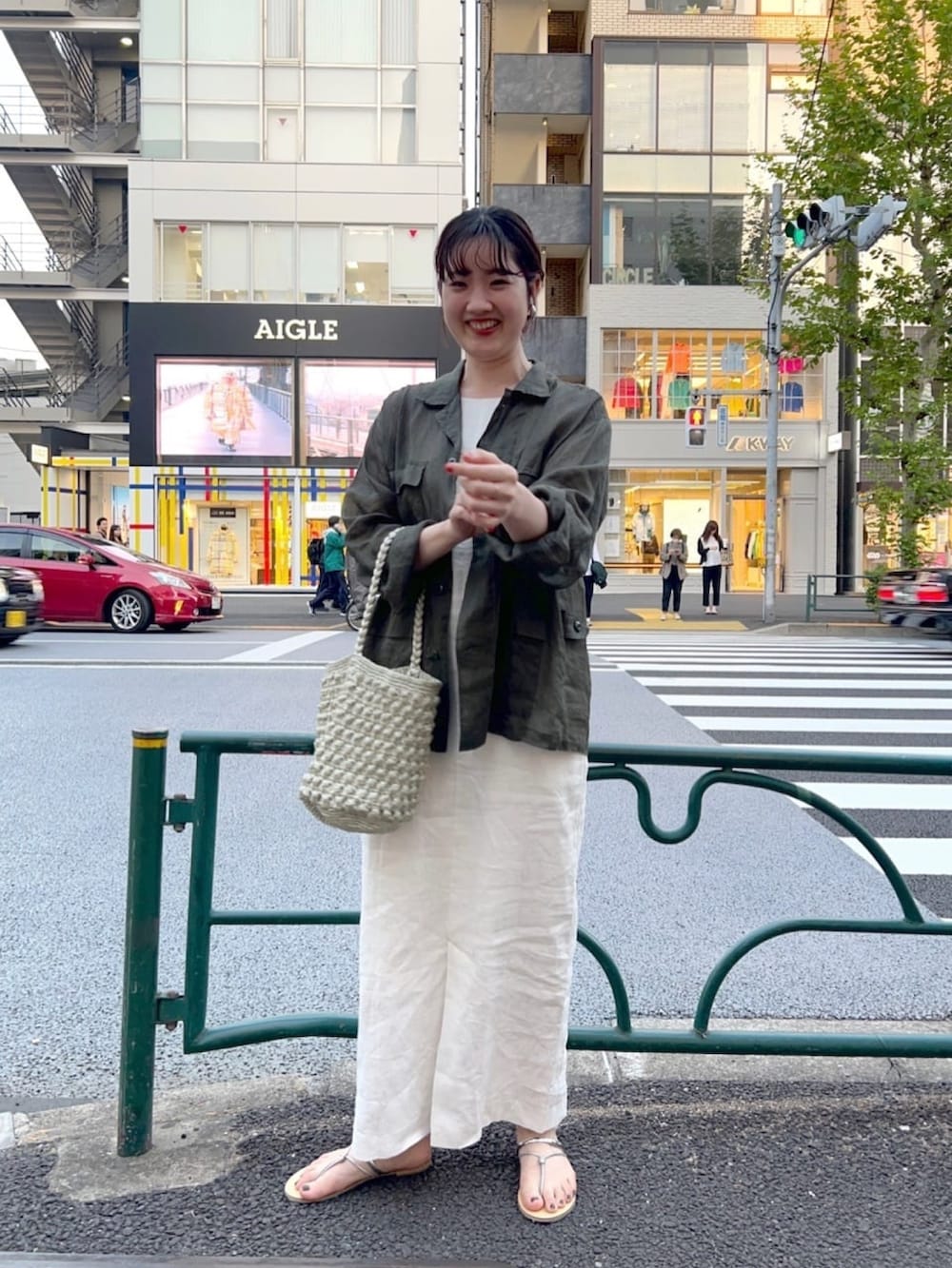 グリーン系のジャケット/アウター、ホワイト系のワンピース、ゴールド系のサンダルを着用したレディースの春コーディネートの2枚目の写真