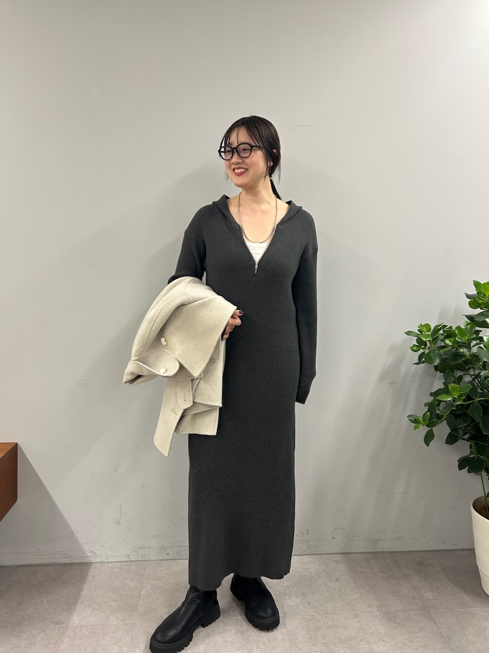 グレー系のワンピース、ブラック系のブーツ、ホワイト系のその他アウターを着用したレディースの秋コーディネートの4枚目の写真
