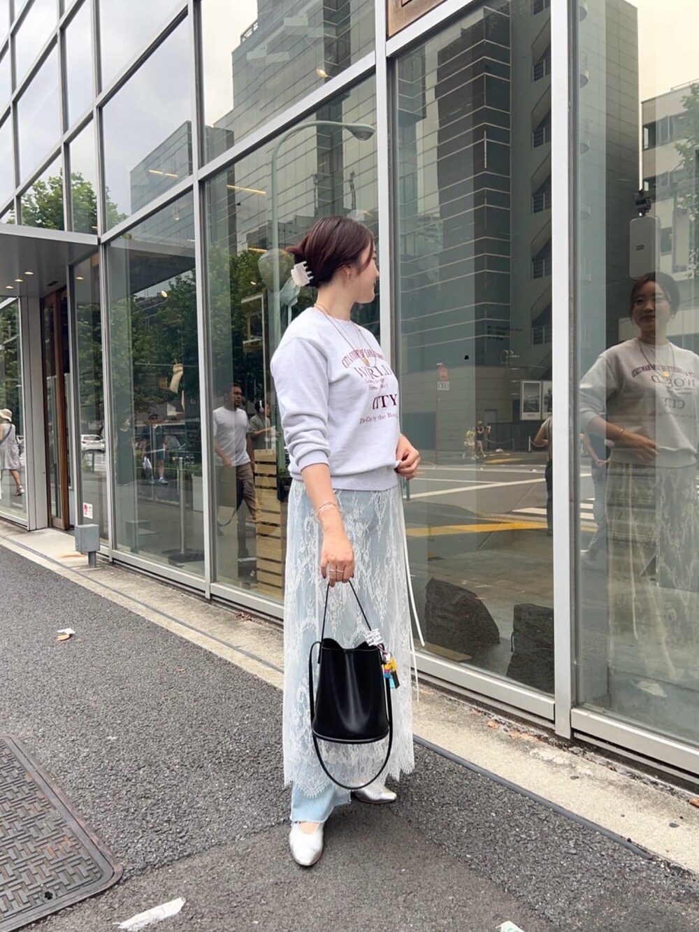 グレー系のTシャツ/カットソー、ブラック系のスカート、ブルー系のデニムパンツを着用したレディースの秋コーディネートの4枚目の写真