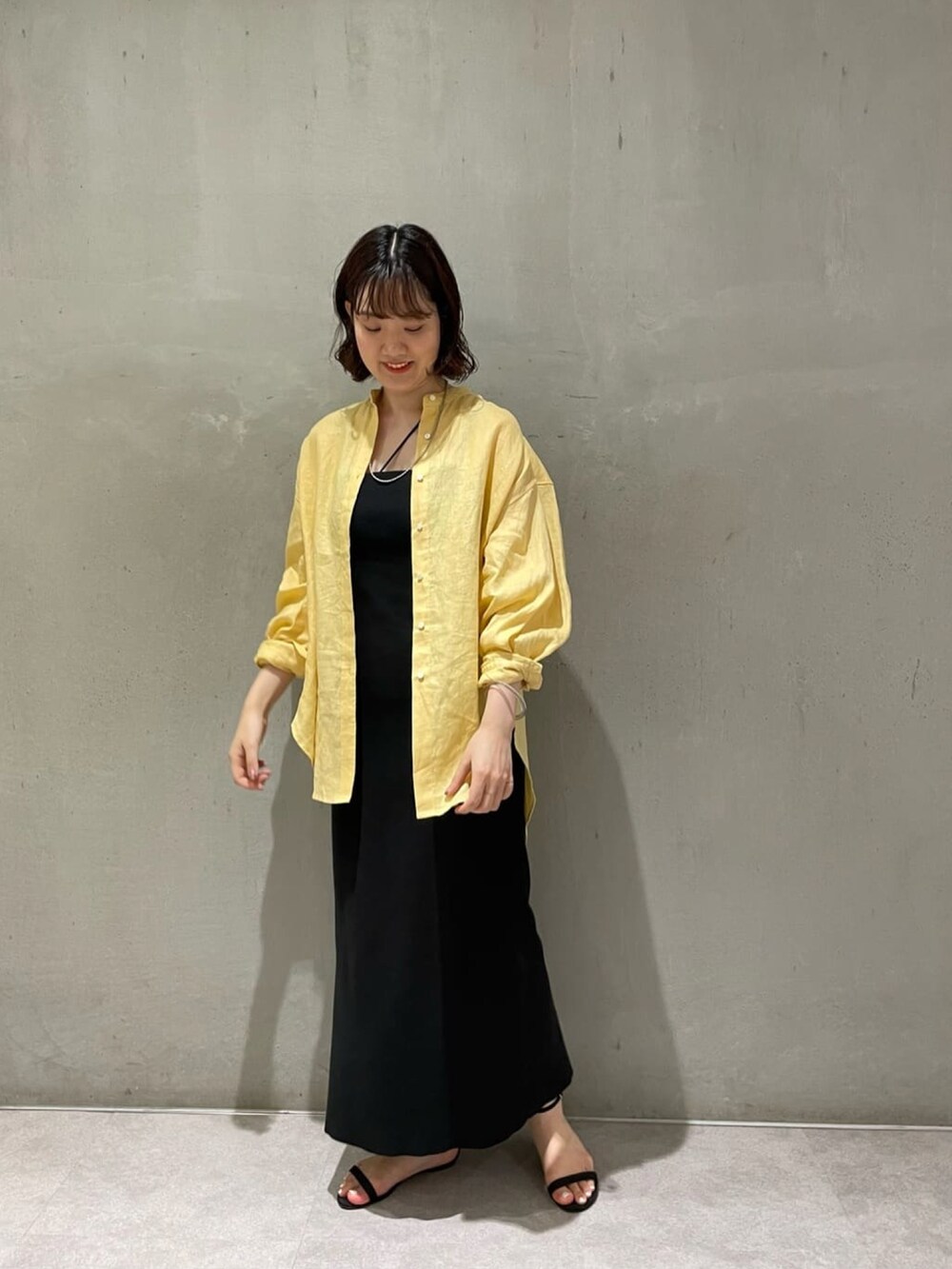 イエロー系のシャツ/ブラウス、ブラック系のワンピース、ブラック系のキャミソールを着用したレディースの夏コーディネートの2枚目の写真