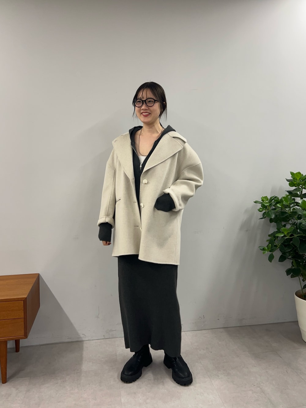 グレー系のワンピース、ブラック系のブーツ、ホワイト系のその他アウターを着用したレディースの秋コーディネートの2枚目の写真