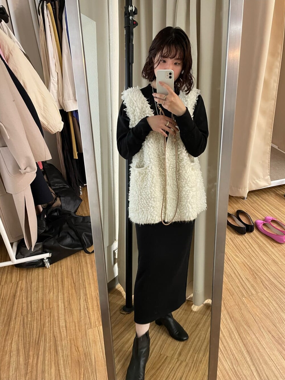 シルバー系のトートバッグ、ブラック系のブーツ、ホワイト系のニット/セーターを着用したレディースの冬コーディネートの3枚目の写真