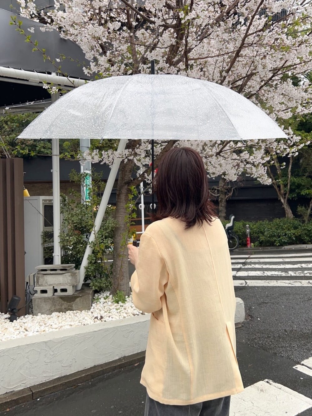 イエロー系のテーラードジャケット、ブラック系のデニムパンツ、シルバー系のネックレスを着用したレディースの春コーディネートの4枚目の写真