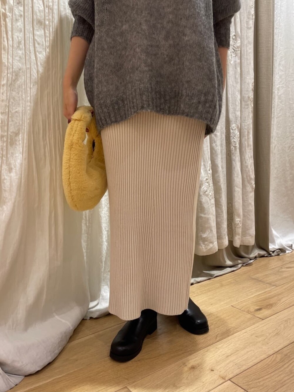 ブルー系のニット/セーター、オレンジ系のハンドバッグ、ホワイト系のスカートを着用したレディースの秋コーディネートの5枚目の写真