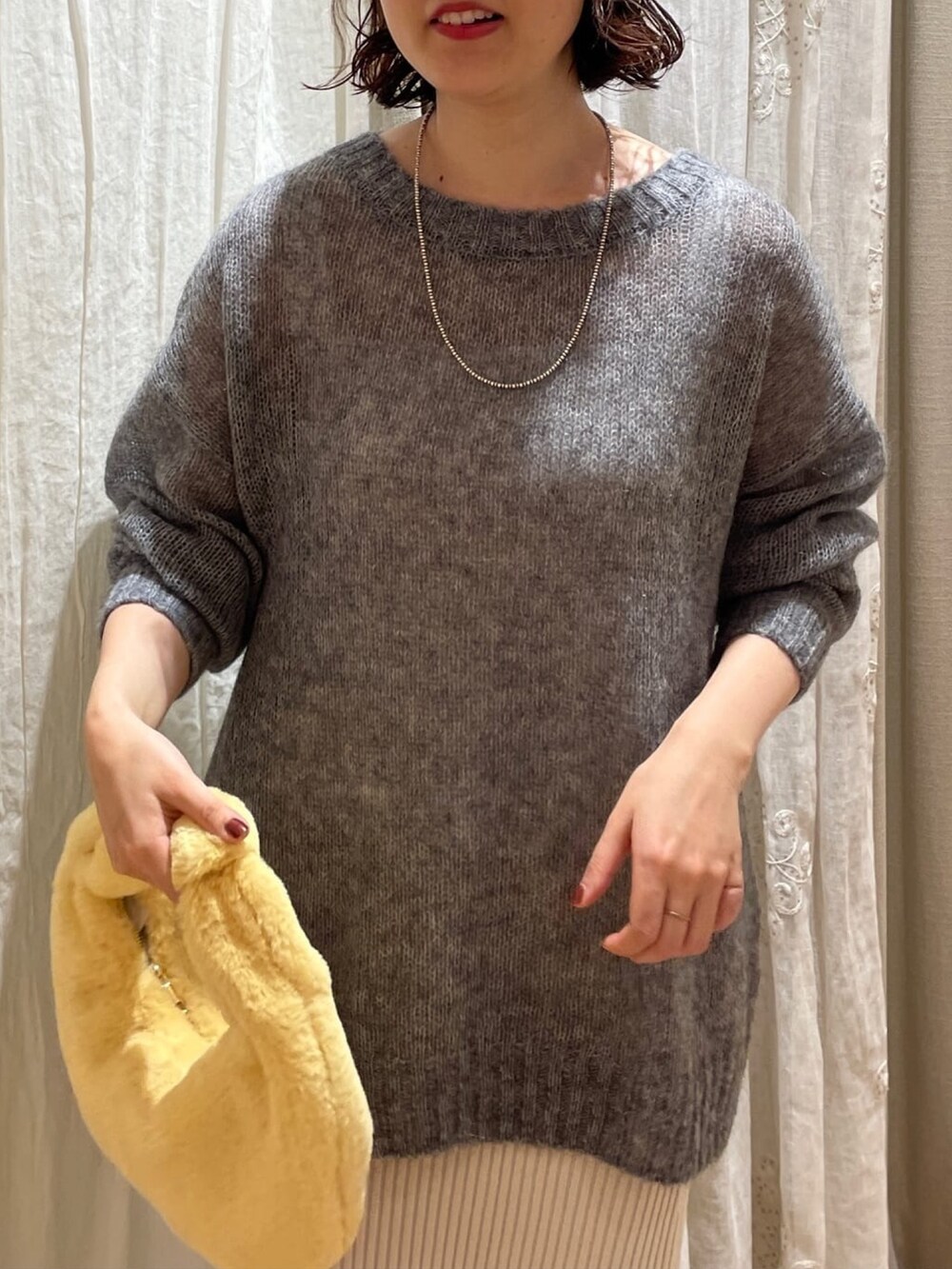 ブルー系のニット/セーター、オレンジ系のハンドバッグ、ホワイト系のスカートを着用したレディースの秋コーディネートの4枚目の写真